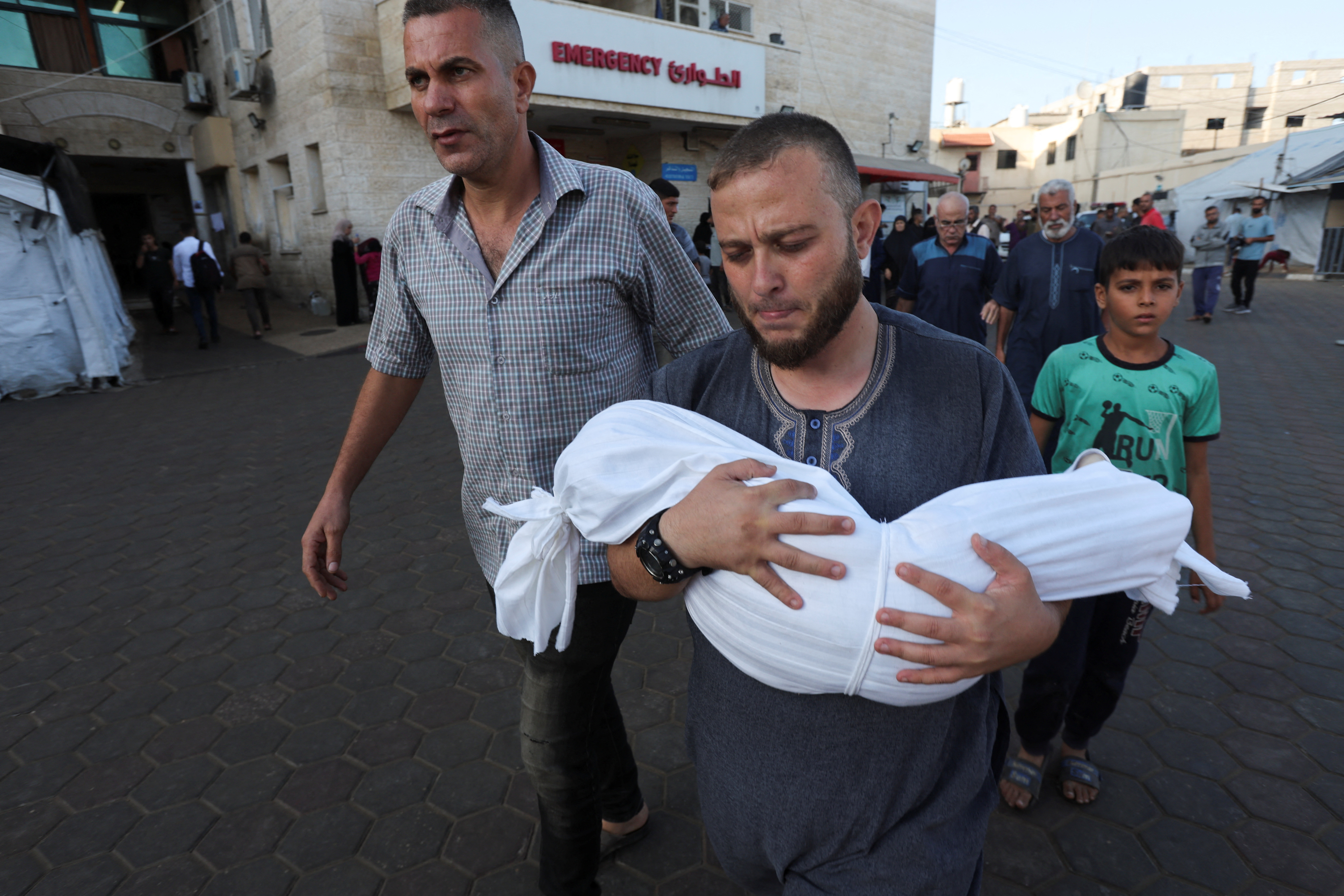 A Palestinian man carries the body of a child who was killed in an Israeli strike on Deir Al-Balah. /Ramadan Abed/Reuters