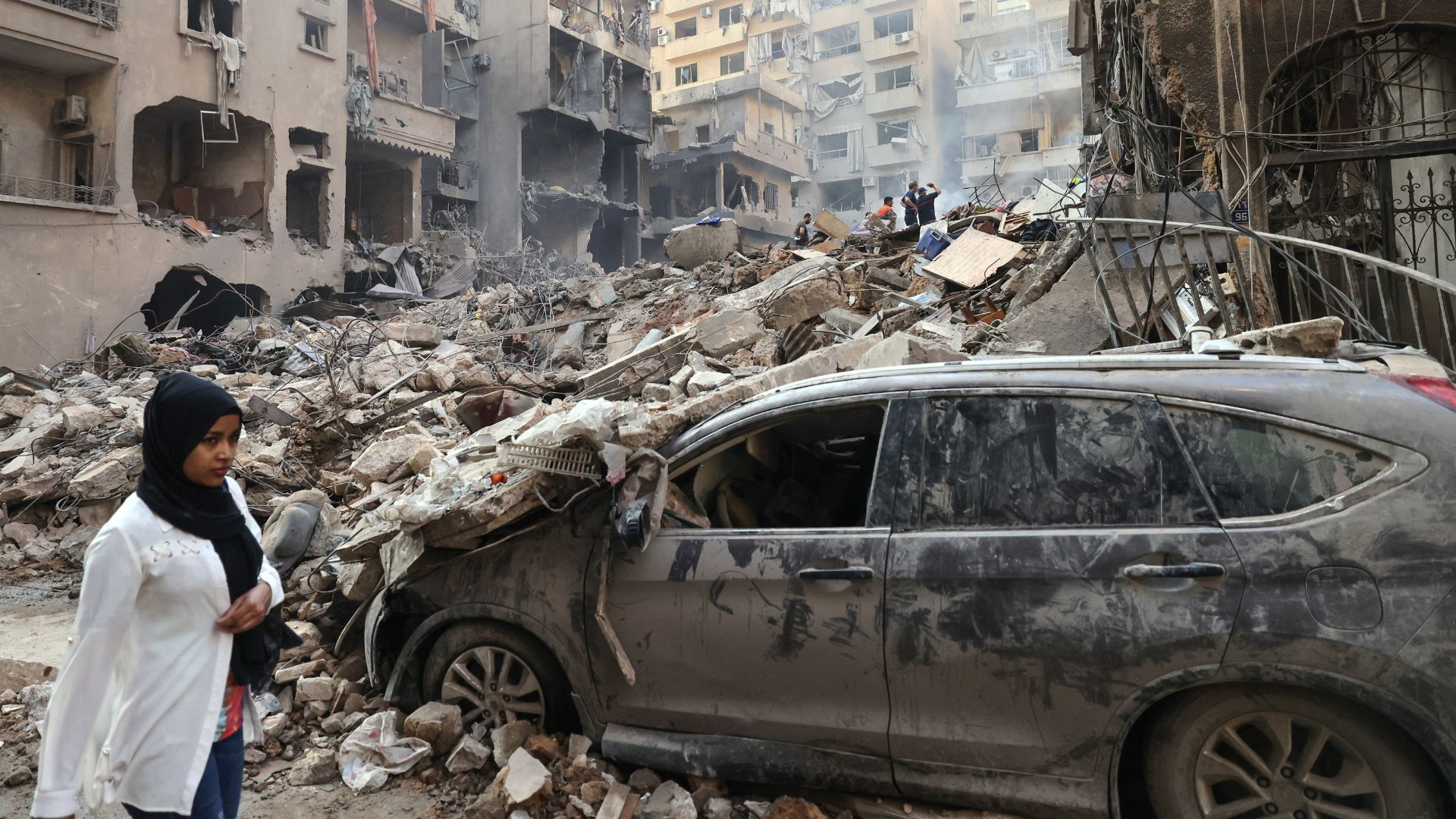 A woman walks past the destruction at the site of an Israeli air strike in the Basta area, Beirut. /Anwar Amro/AFP