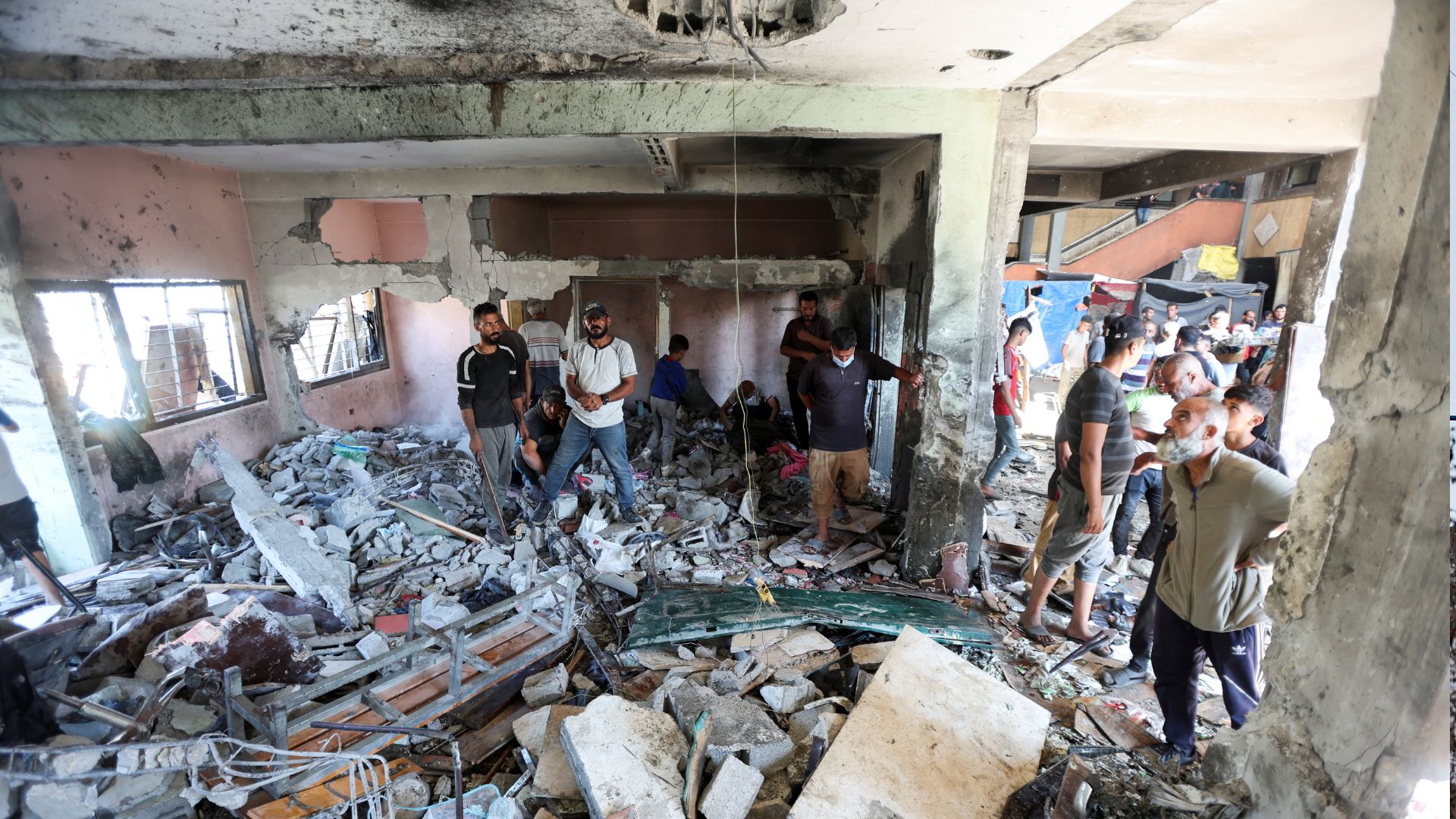 Palestinians inspect the site of an Israeli strike on a school sheltering displaced people in the central Gaza Strip. /Ramadan Abed/Reuters