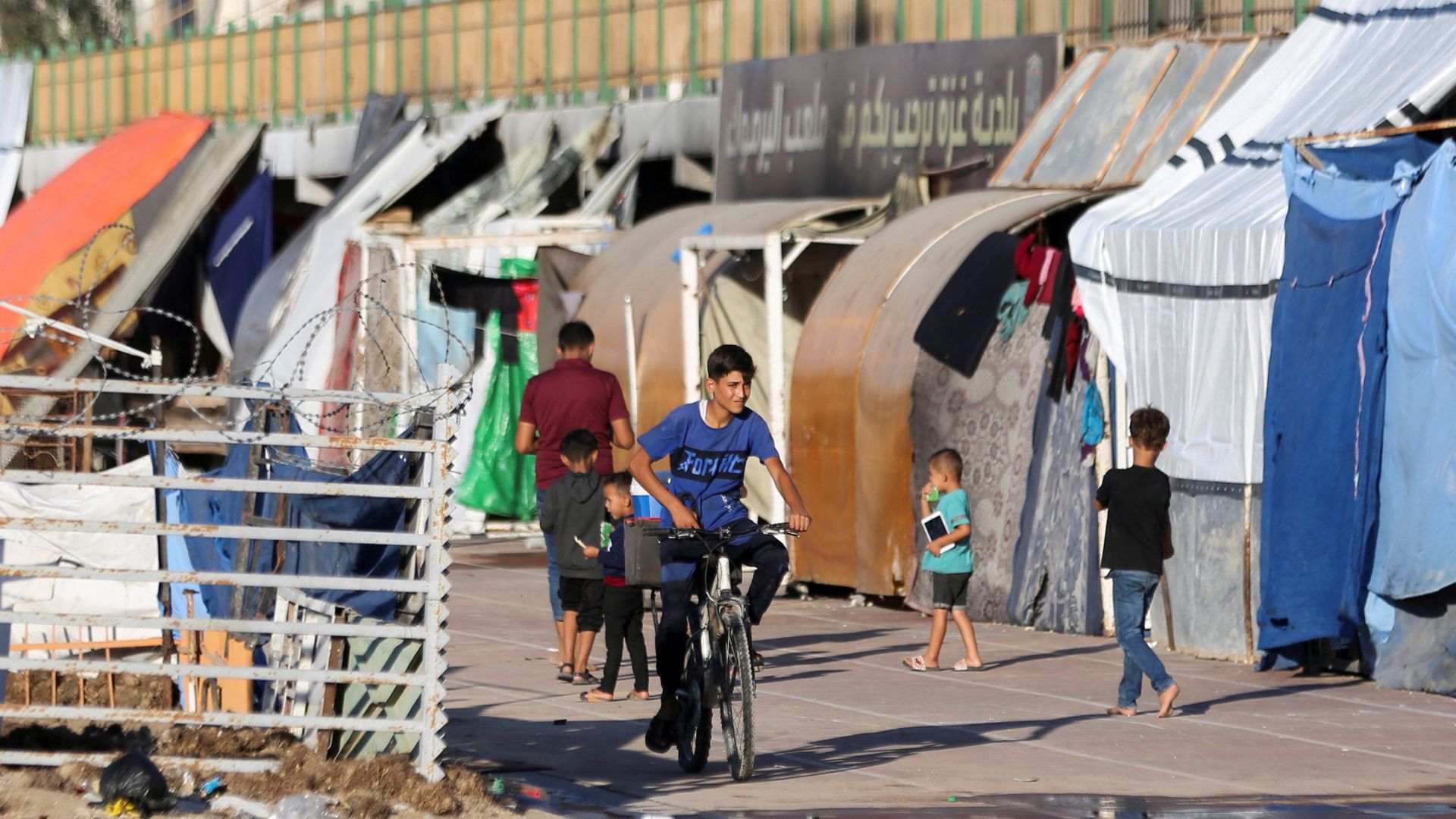 A boy rides a bike as displaced Palestinians, who fled areas in the northern Gaza Strip due to an Israeli evacuation order, take shelter in a stadium in Gaza City. /Dawoud Abu Alkas/Reuters