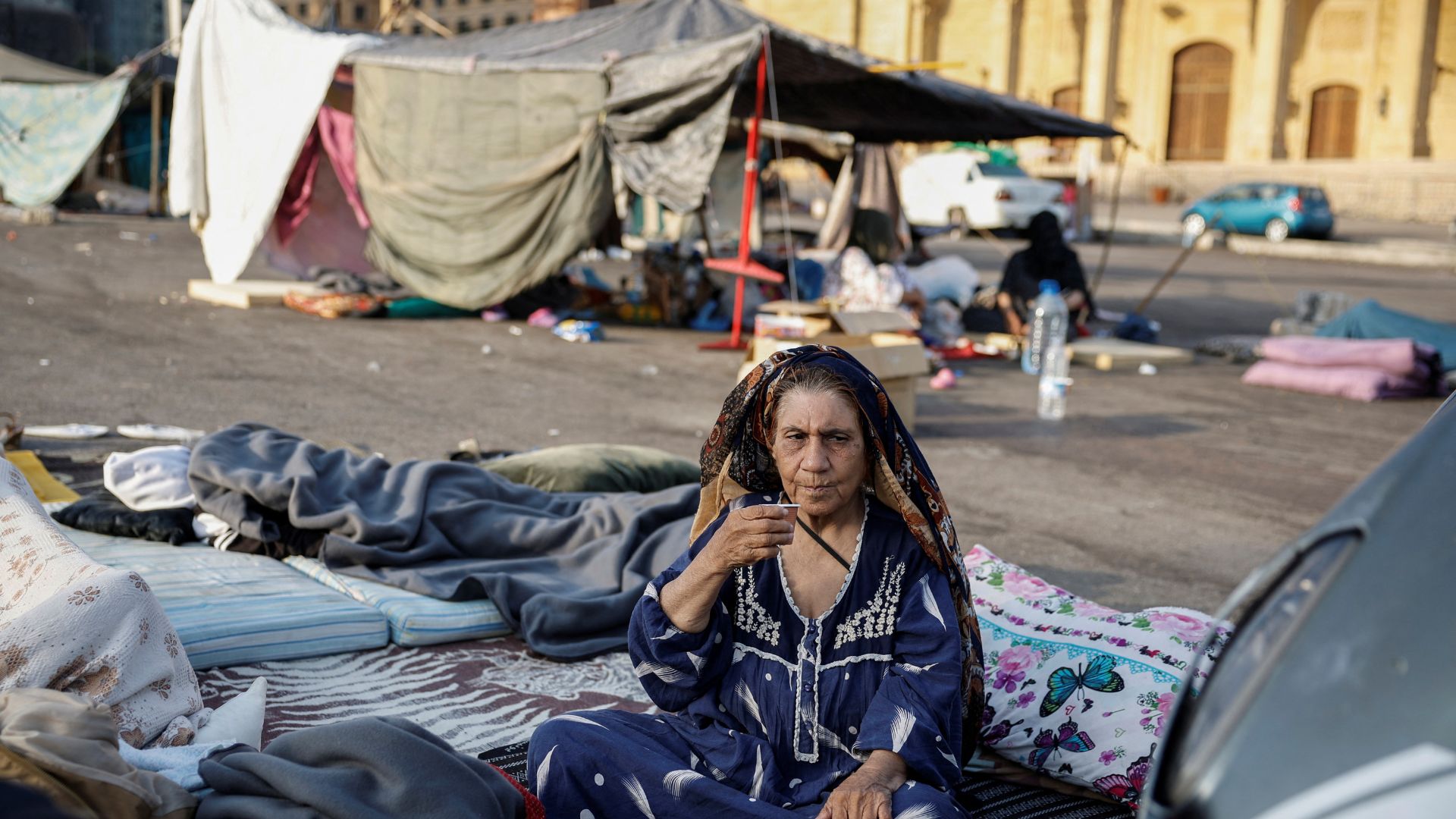 A displaced woman drinks coffee by her makeshift shelter, amid hostilities between Hezbollah and Israeli forces, in central Beirut. /Louisa Gouliamaki/Reuters