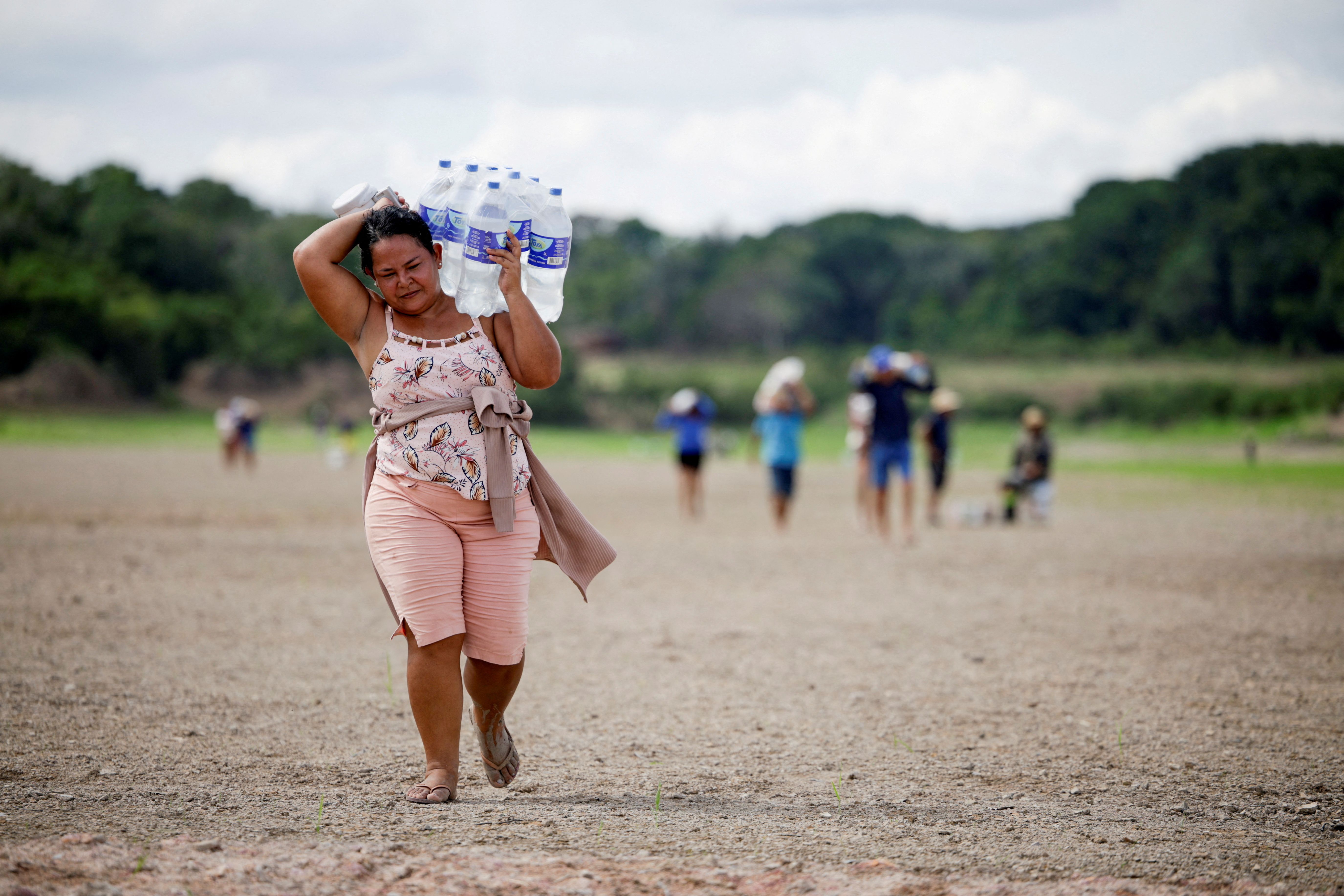 A woman carries water to the isolated villages at the dry Lake Puraquequara during the most intense and widespread drought Brazil has experienced since records began in 1950. /Bruno Kelly/Reuters 