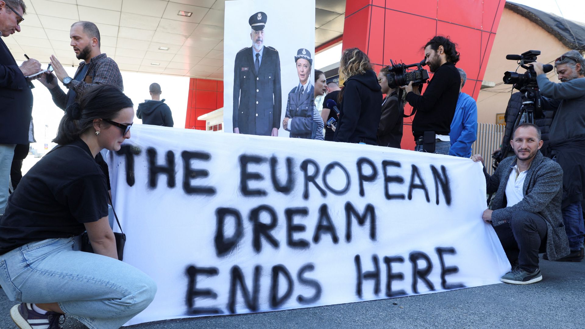 Activists protest next to a poster depicting Albanian Prime Minister Edi Rama and Italian Prime Minister Giorgia Meloni, at Shengjin port. /Florion Goga/Reuters
