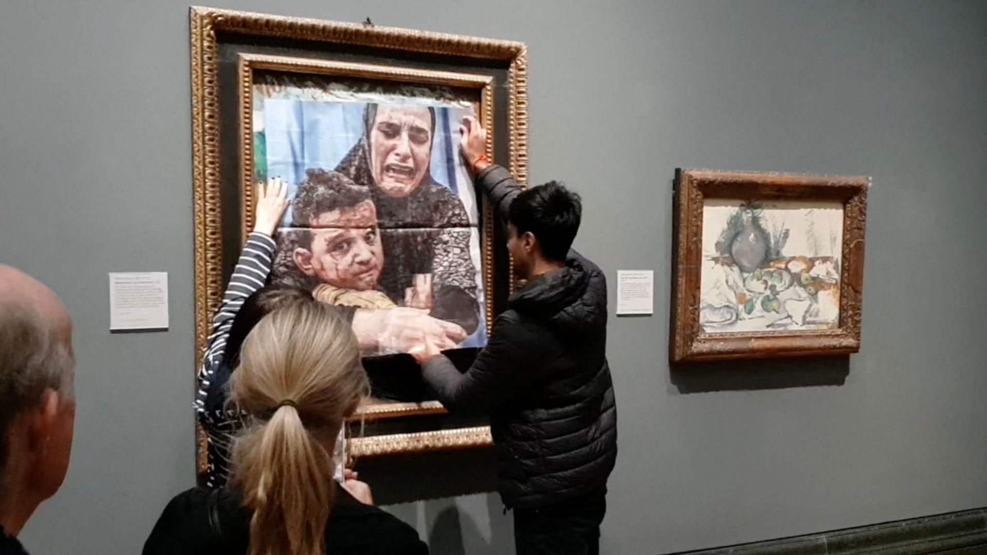 An activist pastes a photo of a Gazan mother and child over Picasso's artwork entitles 'Motherhood' at the National Gallery. /Youth Demand/AFP
