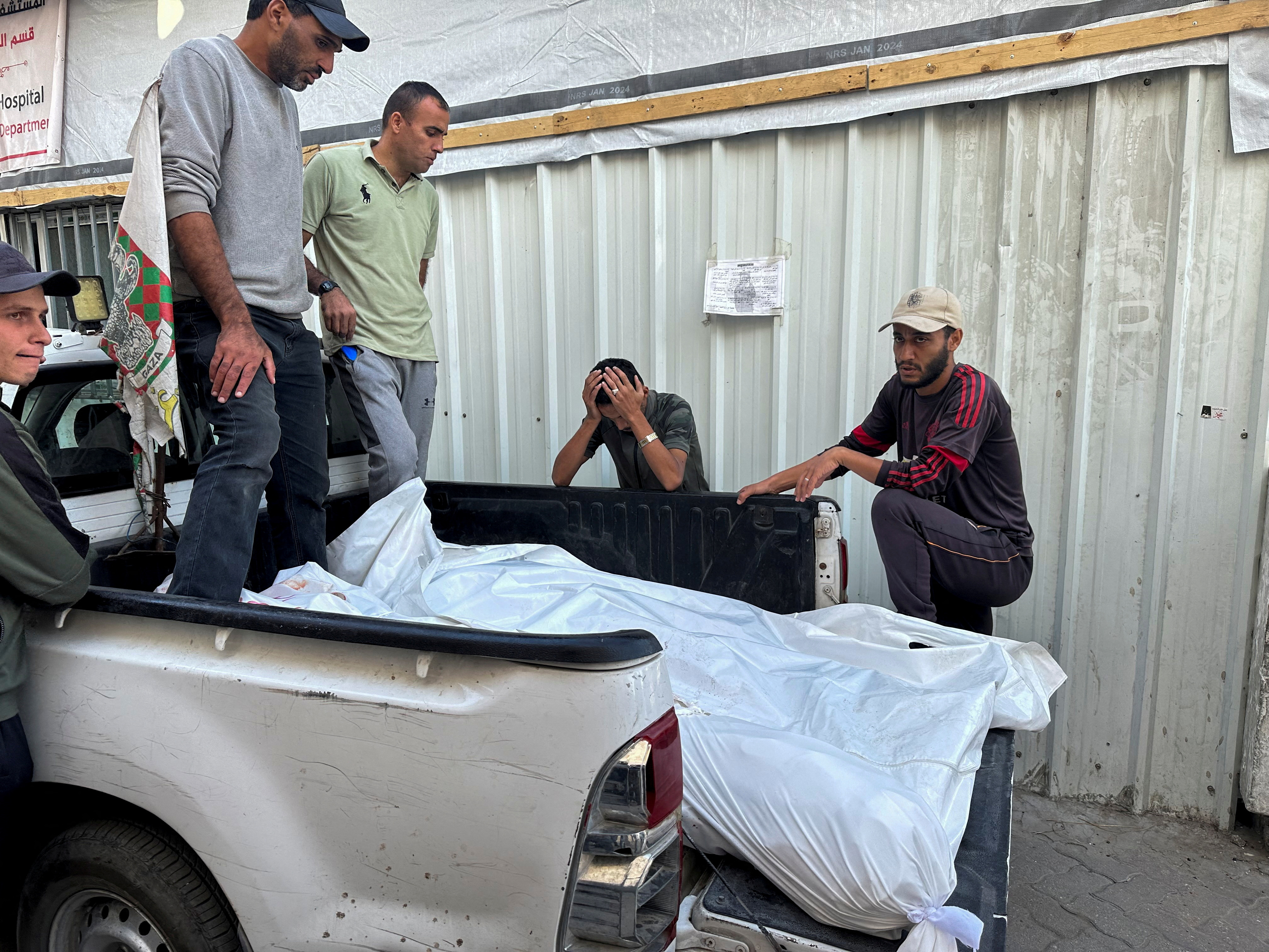 Mourners gather near the bodies of Palestinian municipality workers killed in an Israeli strike on al-Ahli Arab Hospital in Gaza City. The health authority has appealed for more blankets to wrap the bodies of victims. /Hassan Al-Zaanen/Reuters