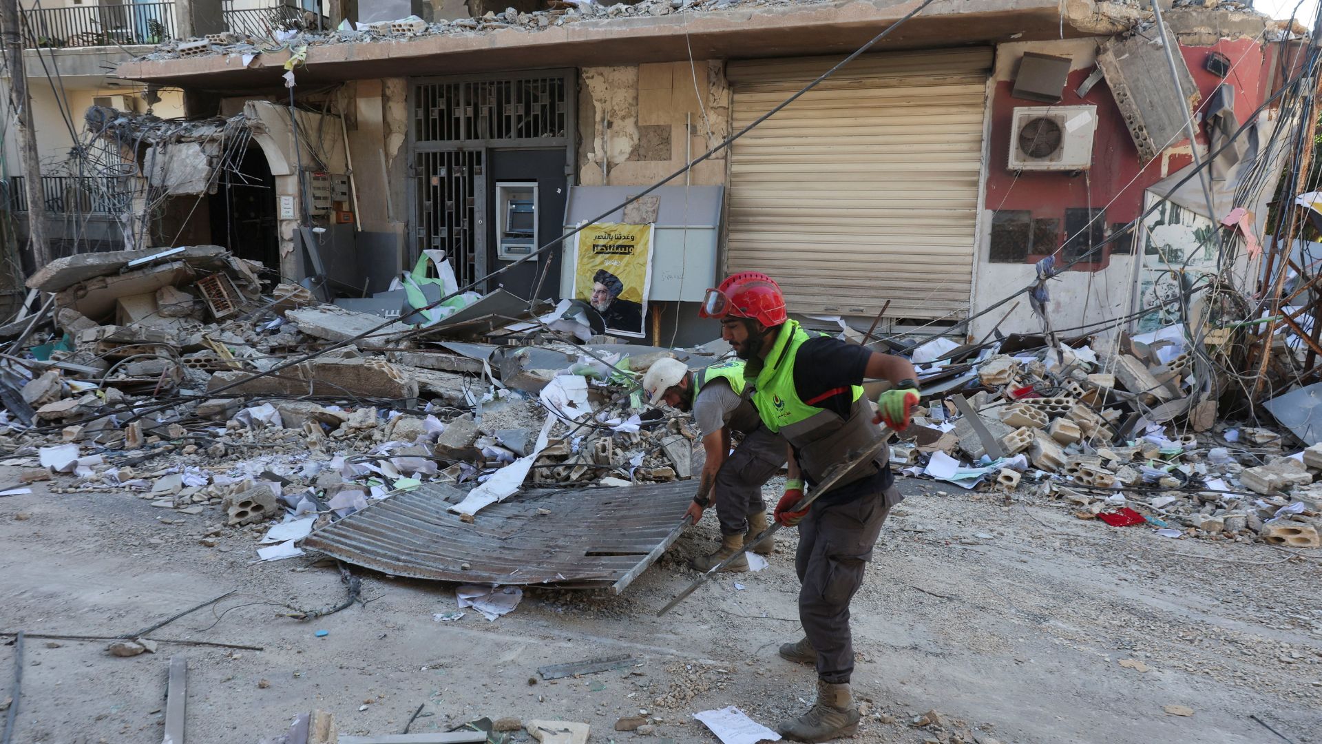 An Islamic Health Authority worker cleans up outside a damaged branch of Qard al-Hassan in Tyre. /Aziz Taher/Reuters
