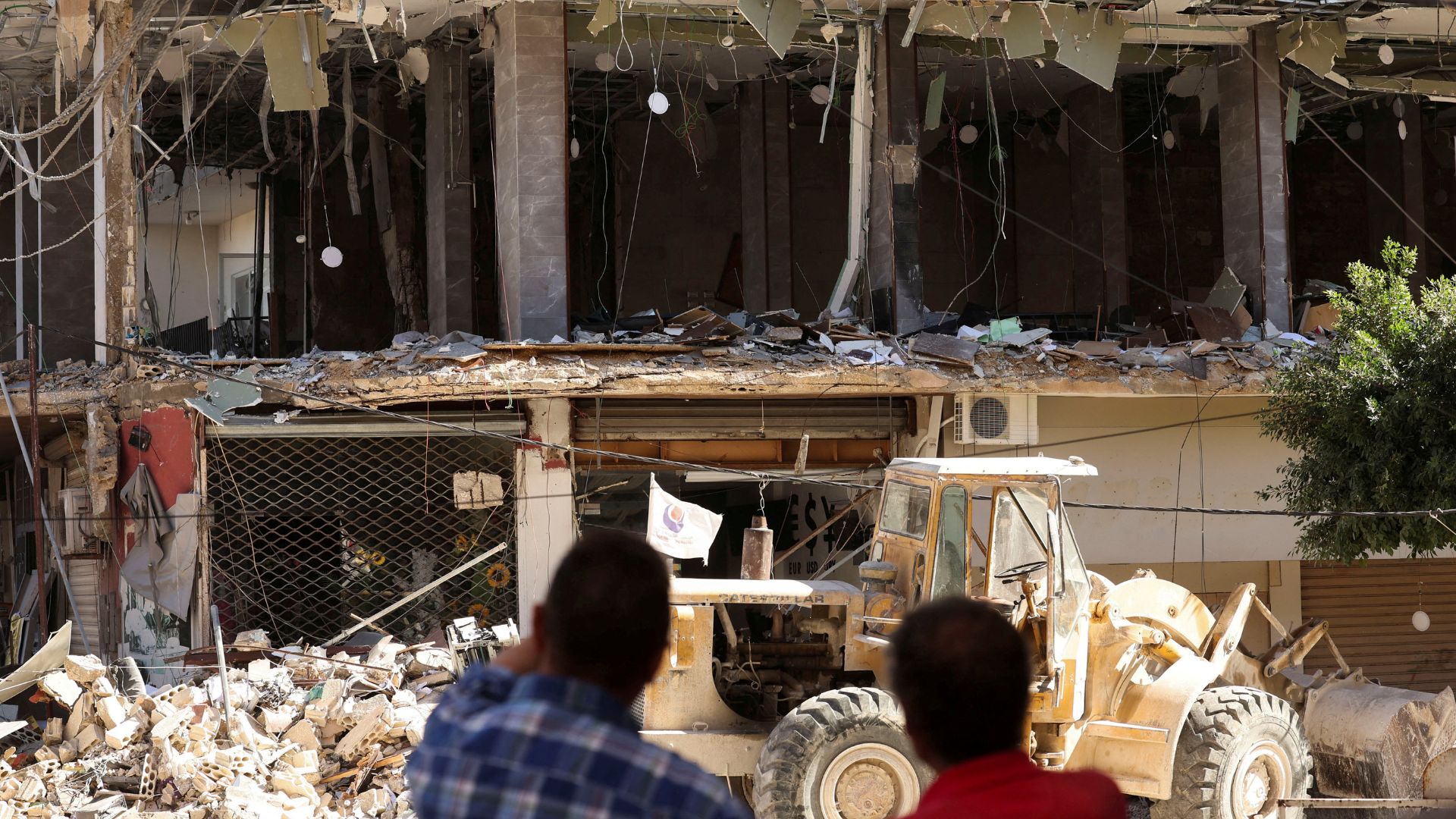 People stand near a damaged branch of Qard al-Hassan in Tyre, Lebanon. /Aziz Taher/Reuters