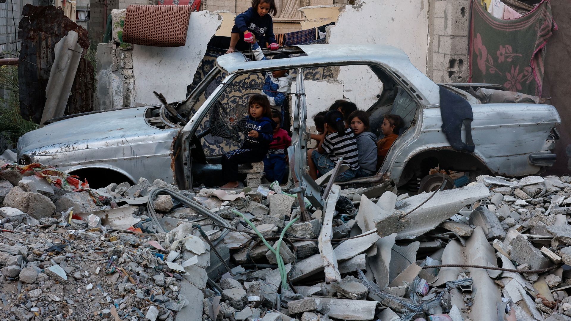 Palestinian children gather at a destroyed vehicle, amid the Israel-Hamas conflict, in Khan Younis, in the southern Gaza Strip. /Mohammed Salem/Reuters