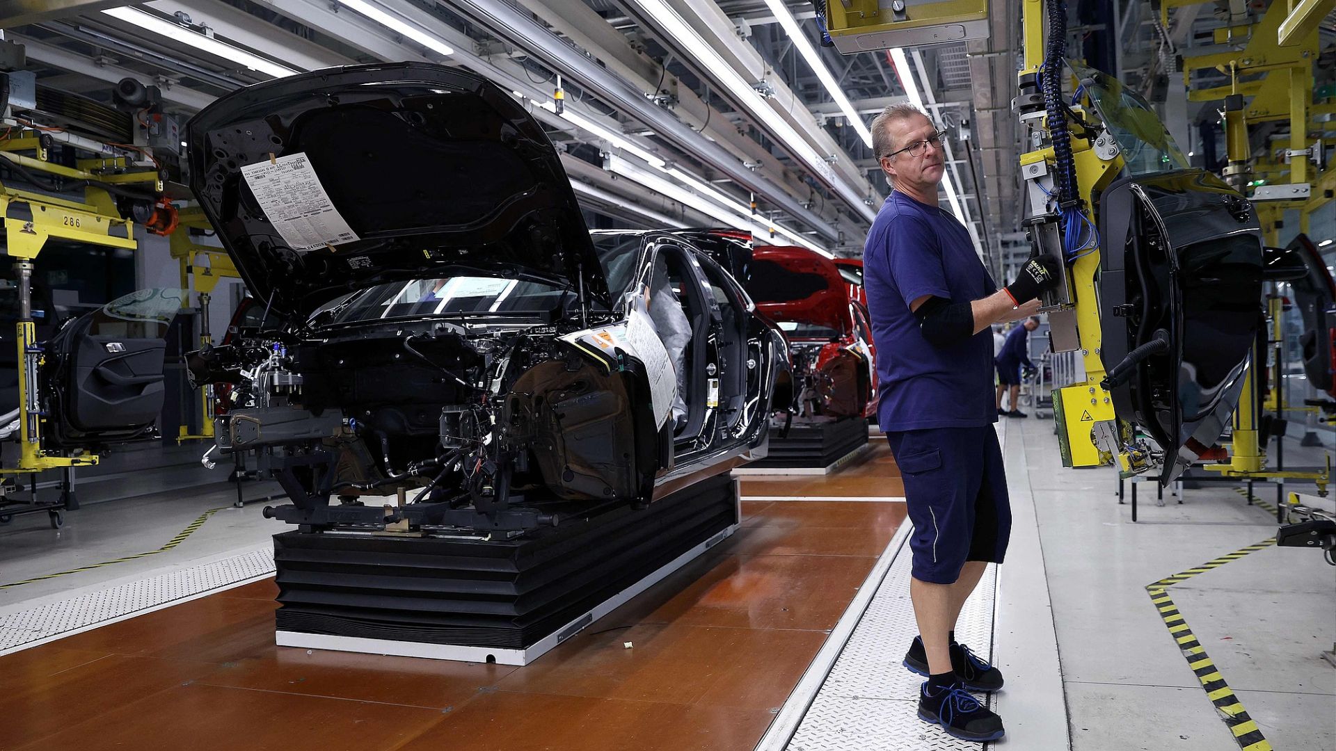 An employee at a BMW factory in Leipzig, Germany, installs a car rear door on the production line. /Ronny Hartmann/CFP
