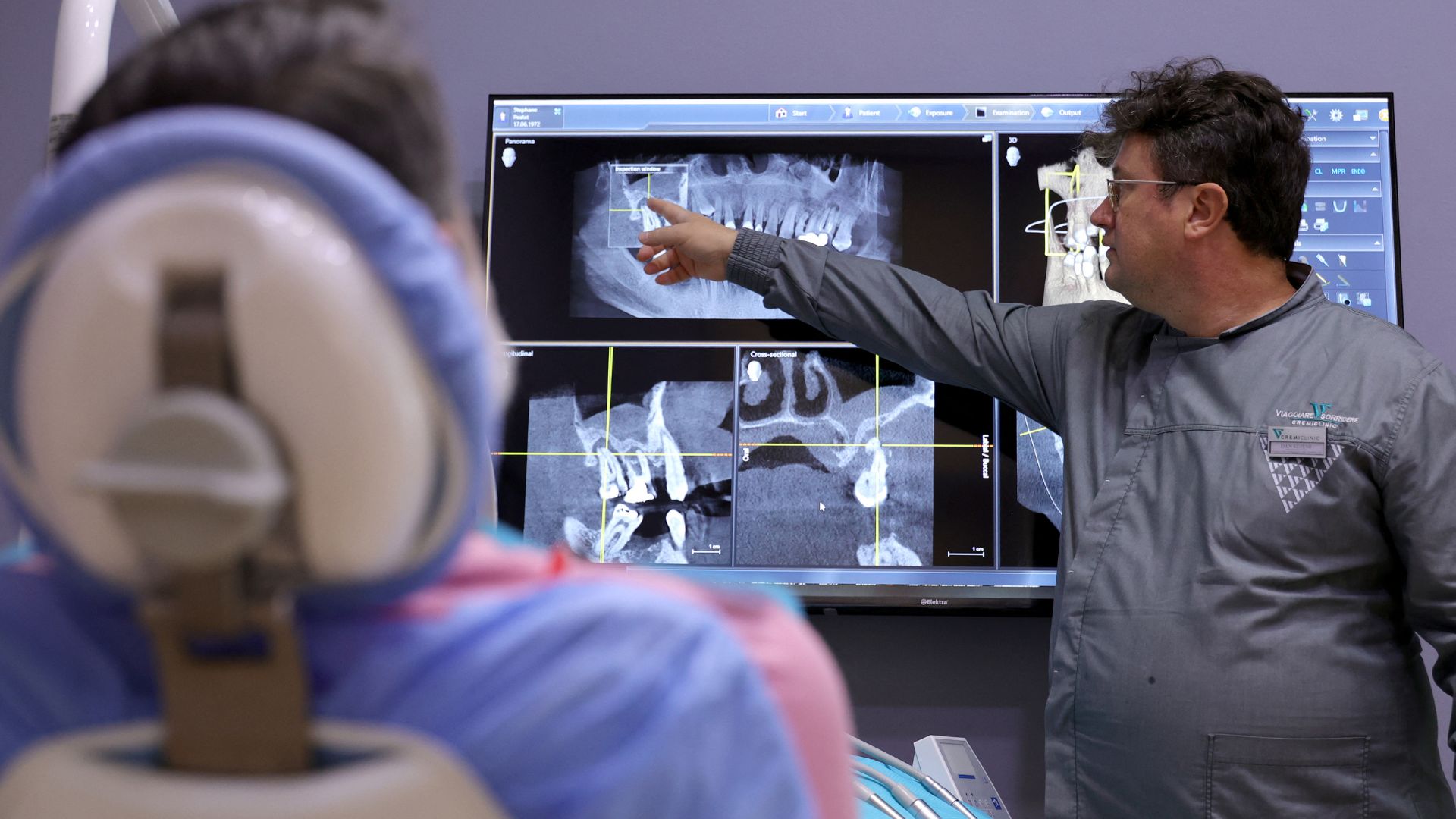 Albanian stomatologist Emin Kuzumi (right) explains the results of a teeth scan at the Gremi Clinic in Tirana. /Adnan Beci/AFP