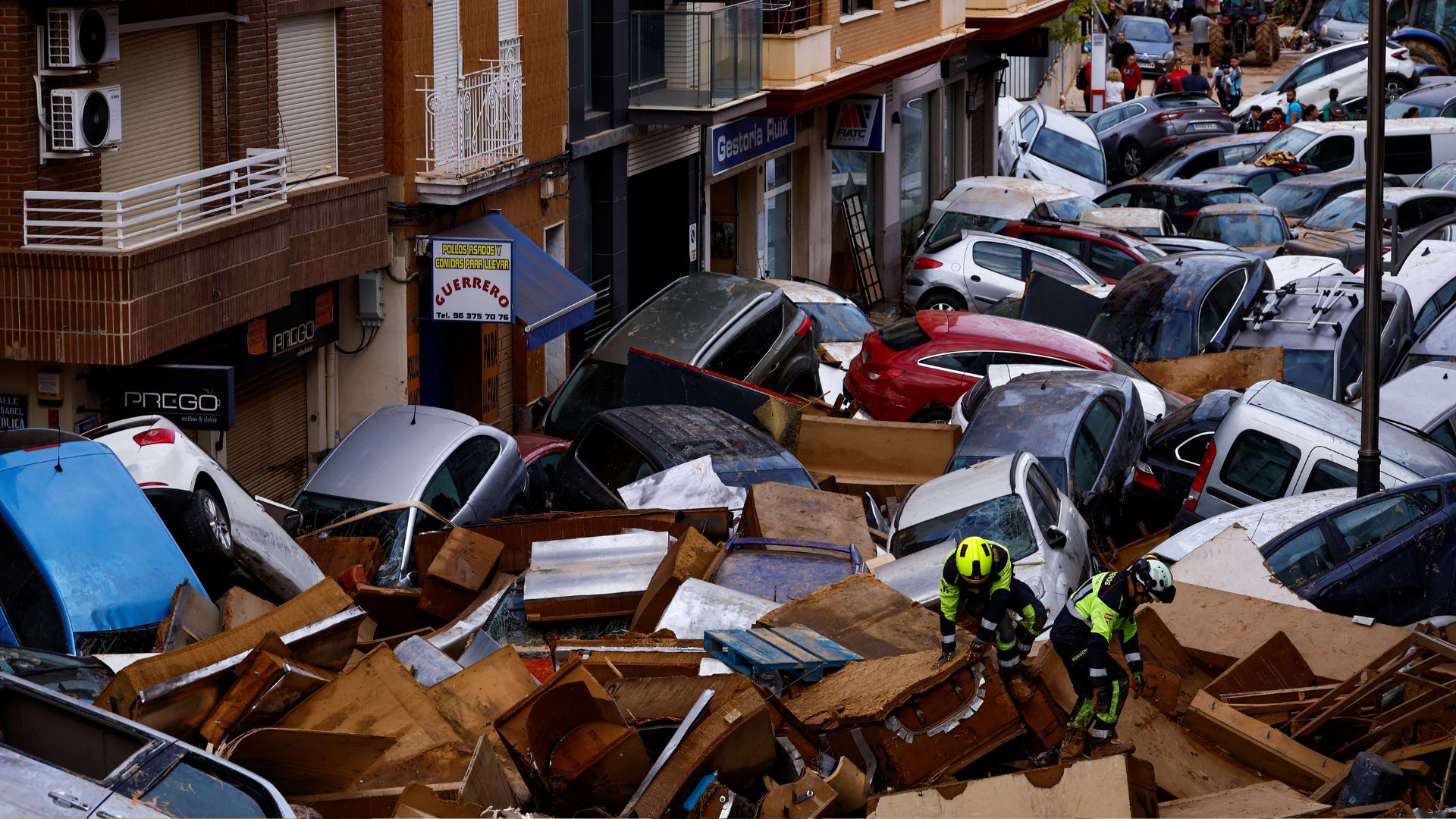 Firefighters walk through piled up cars, following floods in Sedavi, Valencia, Spain. /Susana Vera/Reuters