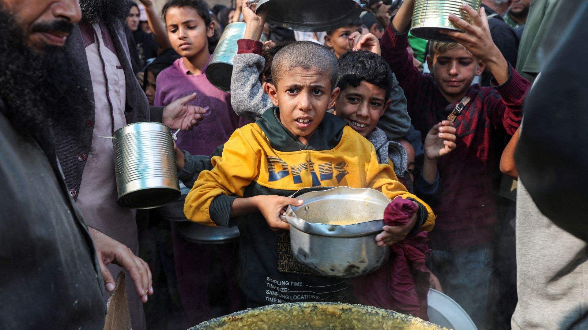 Palestinians gather to receive meals cooked by a charity kitchen in Deir Al-Balah, in the central Gaza Strip. /Ramadan Abed/Reuters