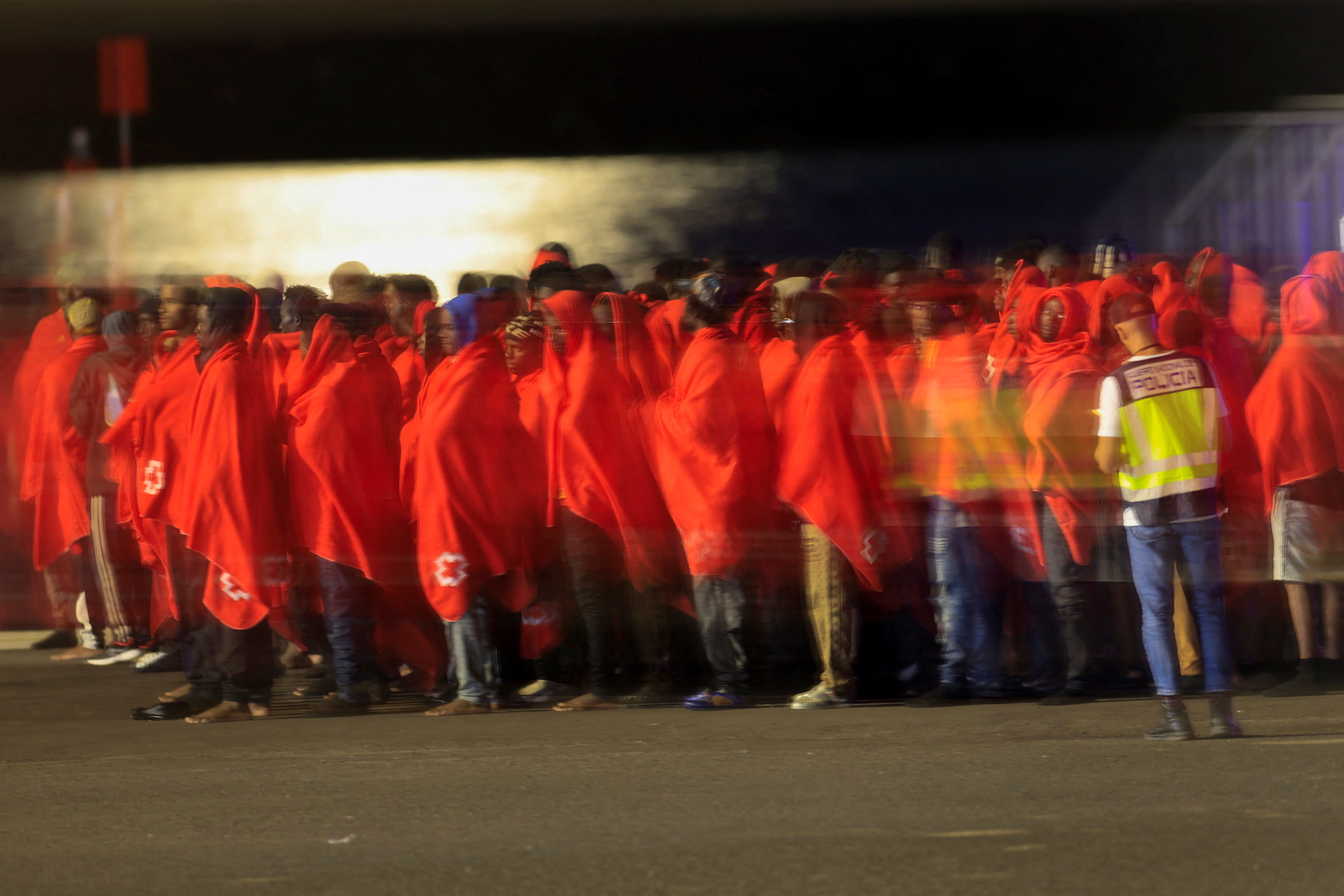 Dozens of migrants wait to be treated by the Red Cross after disembarking from a Spanish coast guard ship in Port Naos, in Arrecife, on the island of Lanzarote on November 5. /Borja Suarez/Reuters