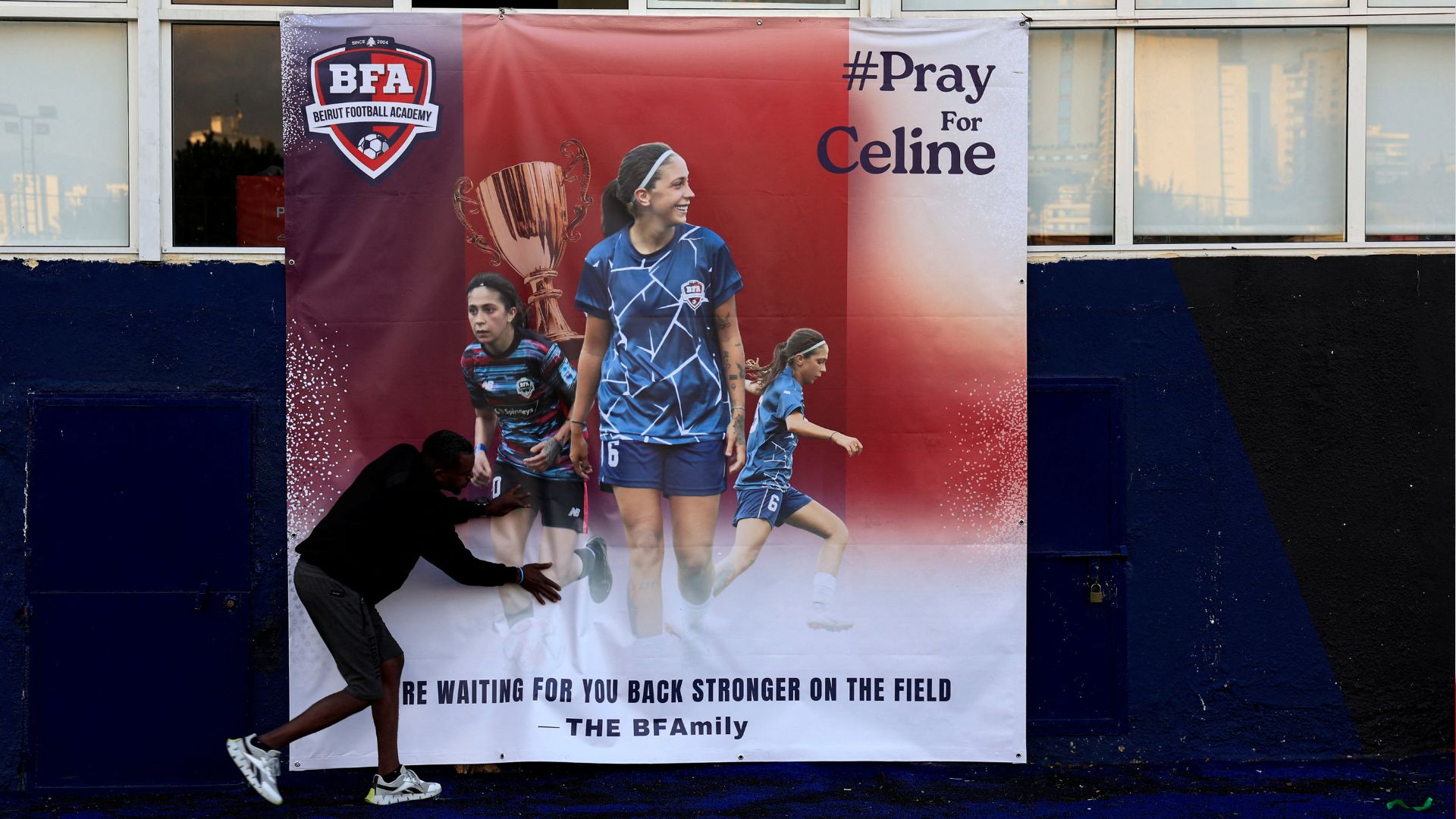 A worker fixes a poster of Celine Haidar at Beirut Football Academy in Furn El Chebbak. /Thaier Al-Sudani/Reuters