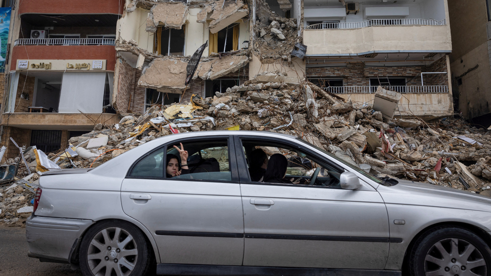 A woman gestures from a car as they drive past a destroyed building, after the ceasefire between Israel and Iran-backed group Hezbollah took effect, in Tyre, Lebanon, November. /Adnan Abidi/Reuters
