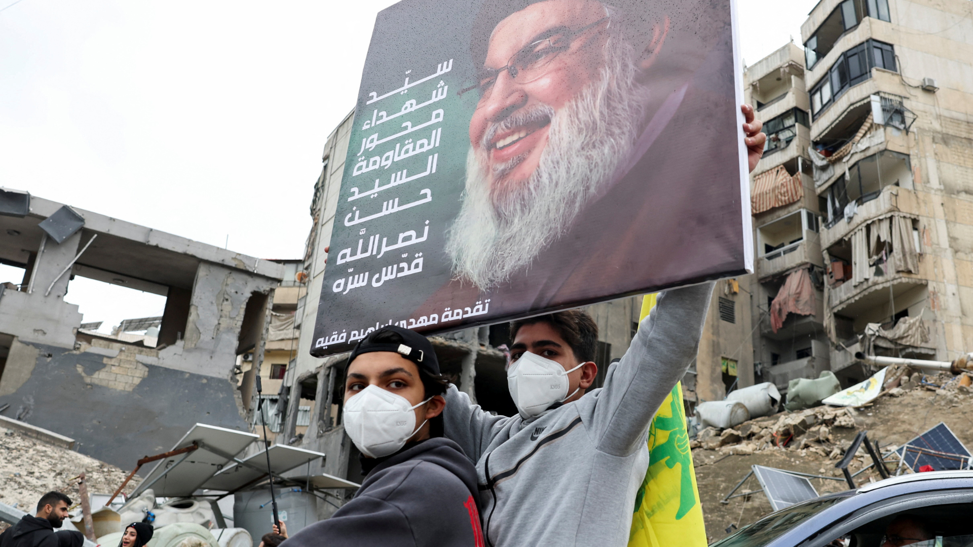 A youth holds up a picture of late Hezbollah leader Sayyed Hassan Nasrallah, near damaged buildings in Beirut's southern suburbs, after the ceasefire took effect. /Mohamed Azakir/Reuters
