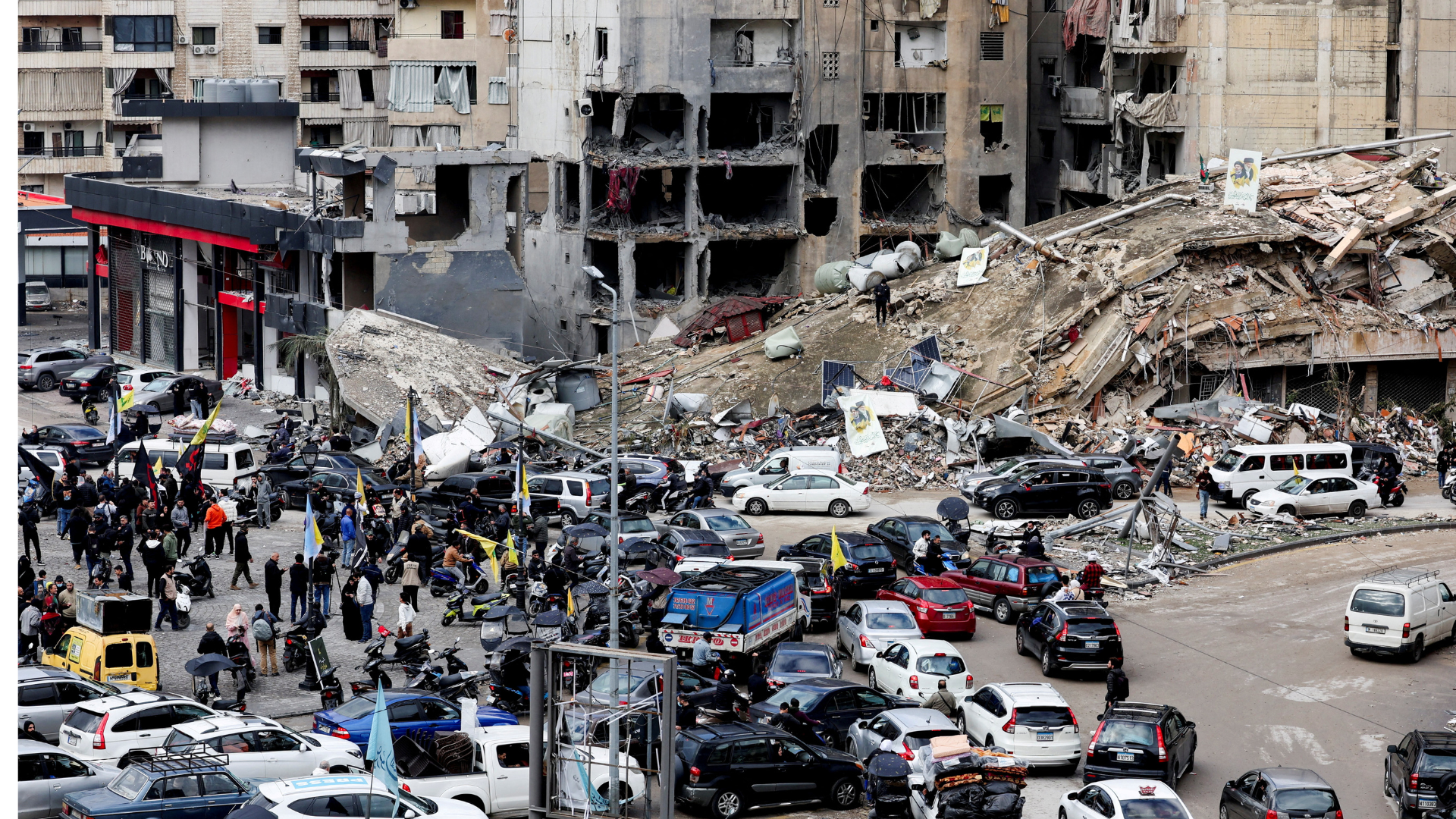 People gather as vehicles drive near damaged buildings, in Beirut's southern suburbs, after the ceasefire took effect. /Mohamed Azakir/Reuters
