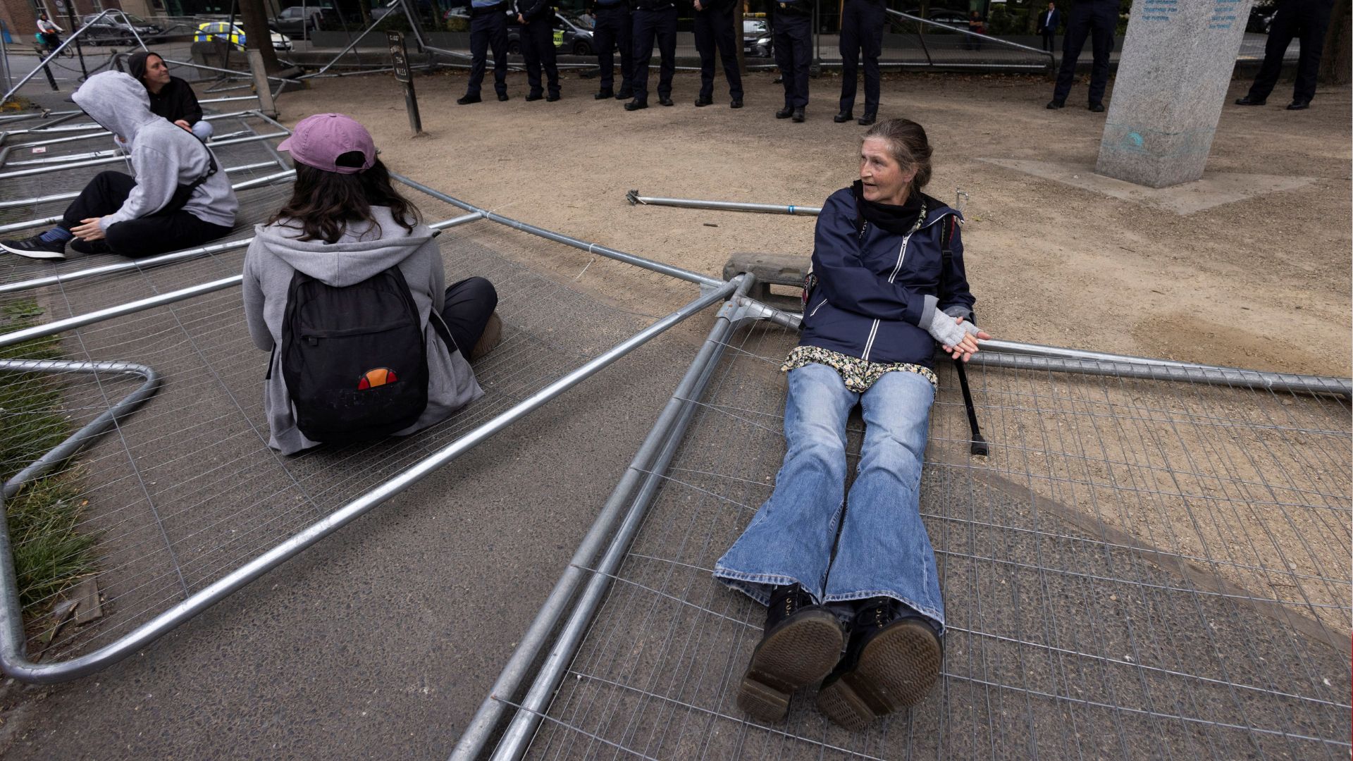 People sit on fences pulled down by demonstrators in protest against the Government's practice of fencing off public spaces and canal ways to prevent homeless and migrant encampments, in Dublin in August. /Clodagh Kilcoyne/Reuters
