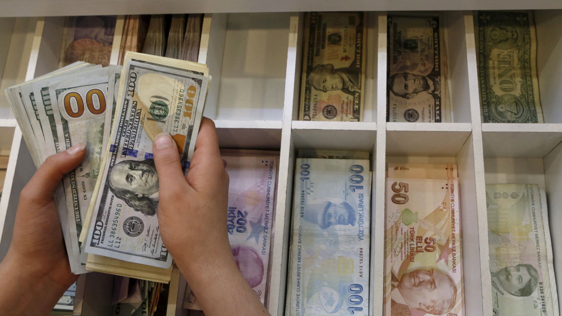 A money changer counts U.S. dollar bills, with Turkish lira banknotes in the background, at an currency exchange office in central Istanbul. /Murad Sezer/Reuters/Archive