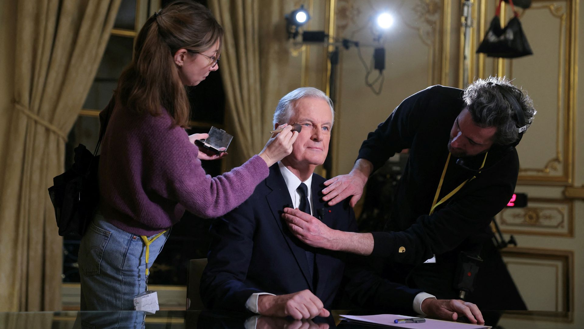 Barnier receives makeup touch-ups before a TV interview on Tuesday night. /Thomas Samson/Pool via Reuters
