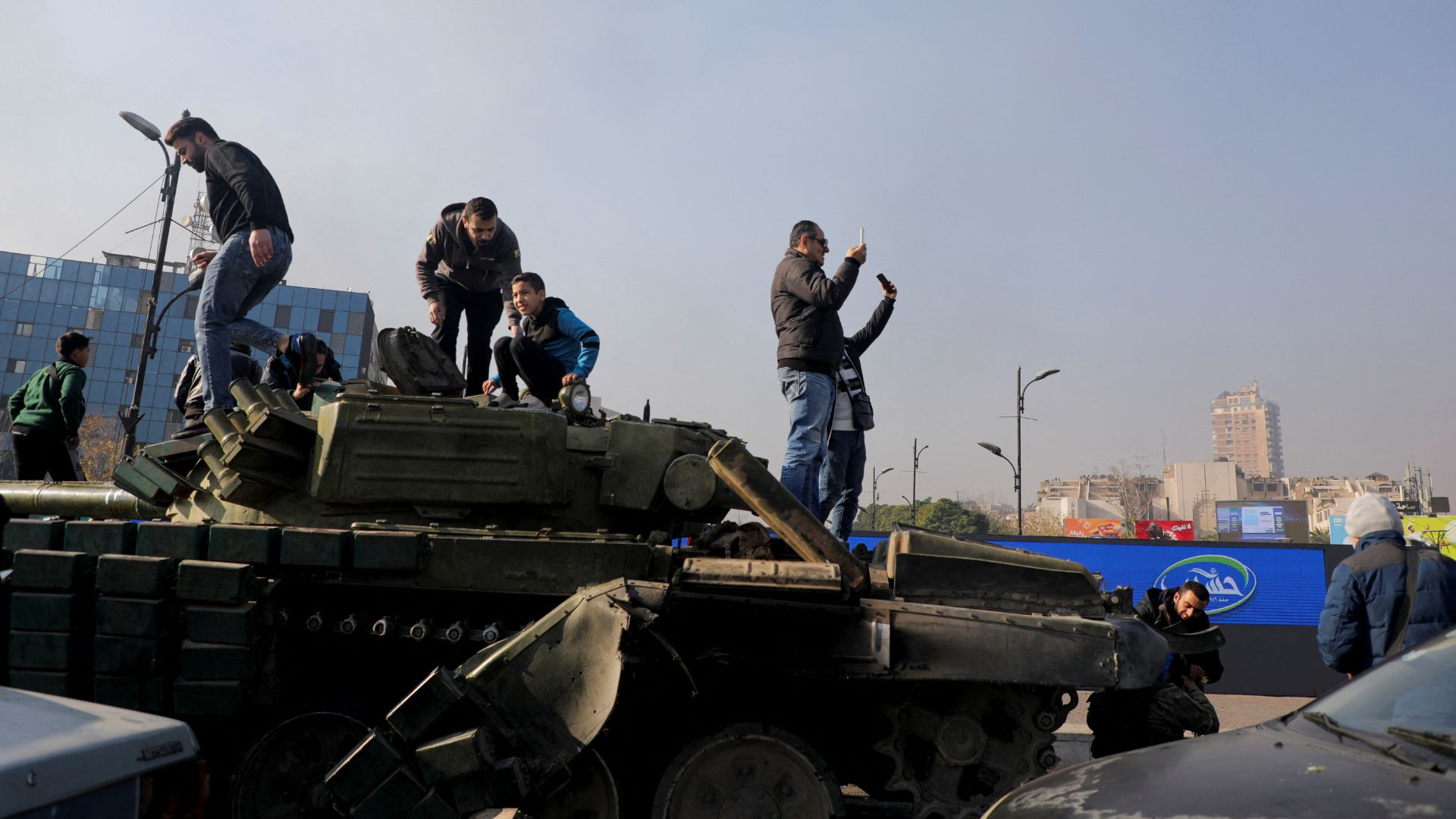 Members of the public stand on a military vehicle in Damascus on Monday. /Mahmoud Hassano/Reuters