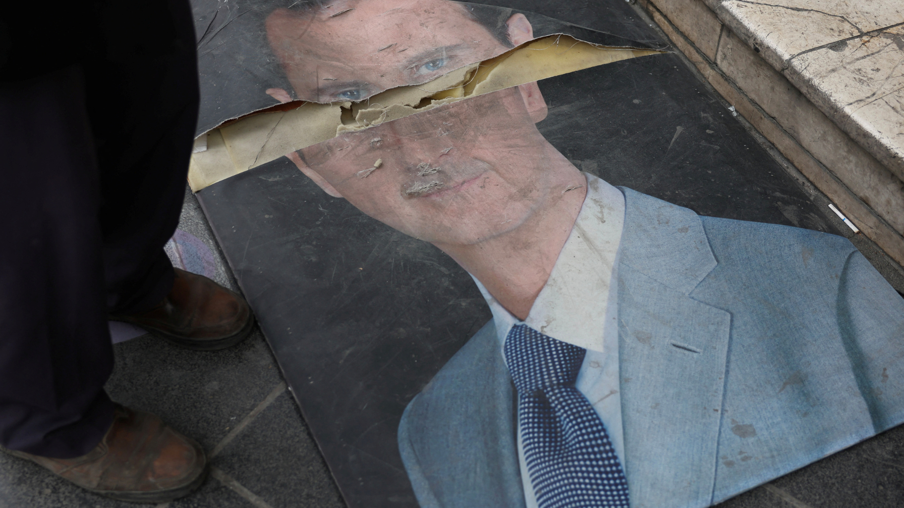 A damaged picture of Syria's former leader in Damascus after rebels seized the capital./ Mohamed Azakir/Reuters