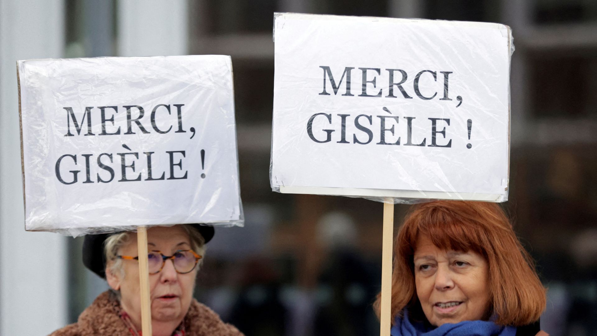 Two women hold placards reading 