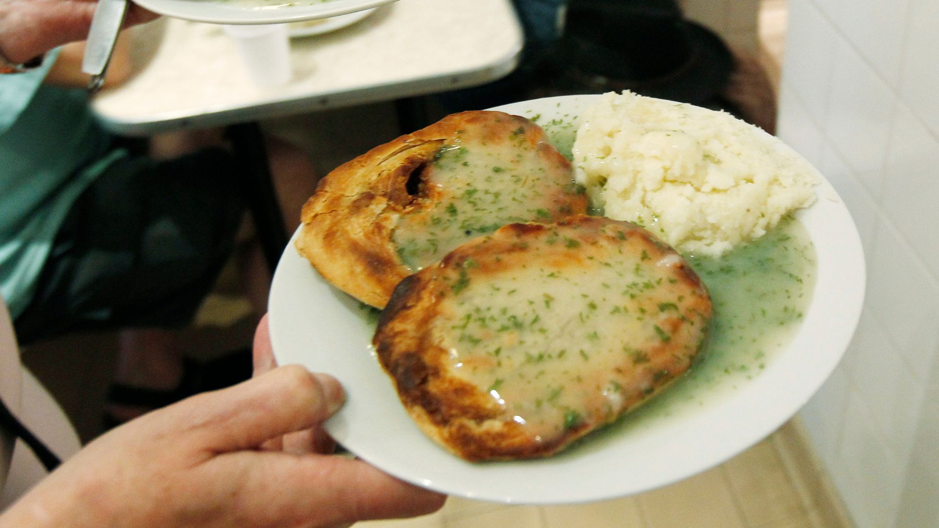 Pies, mash and liquor are delivered to a table at G. Kelly's pie and mash shop in east London. /Suzanne Plunkett/Reuters