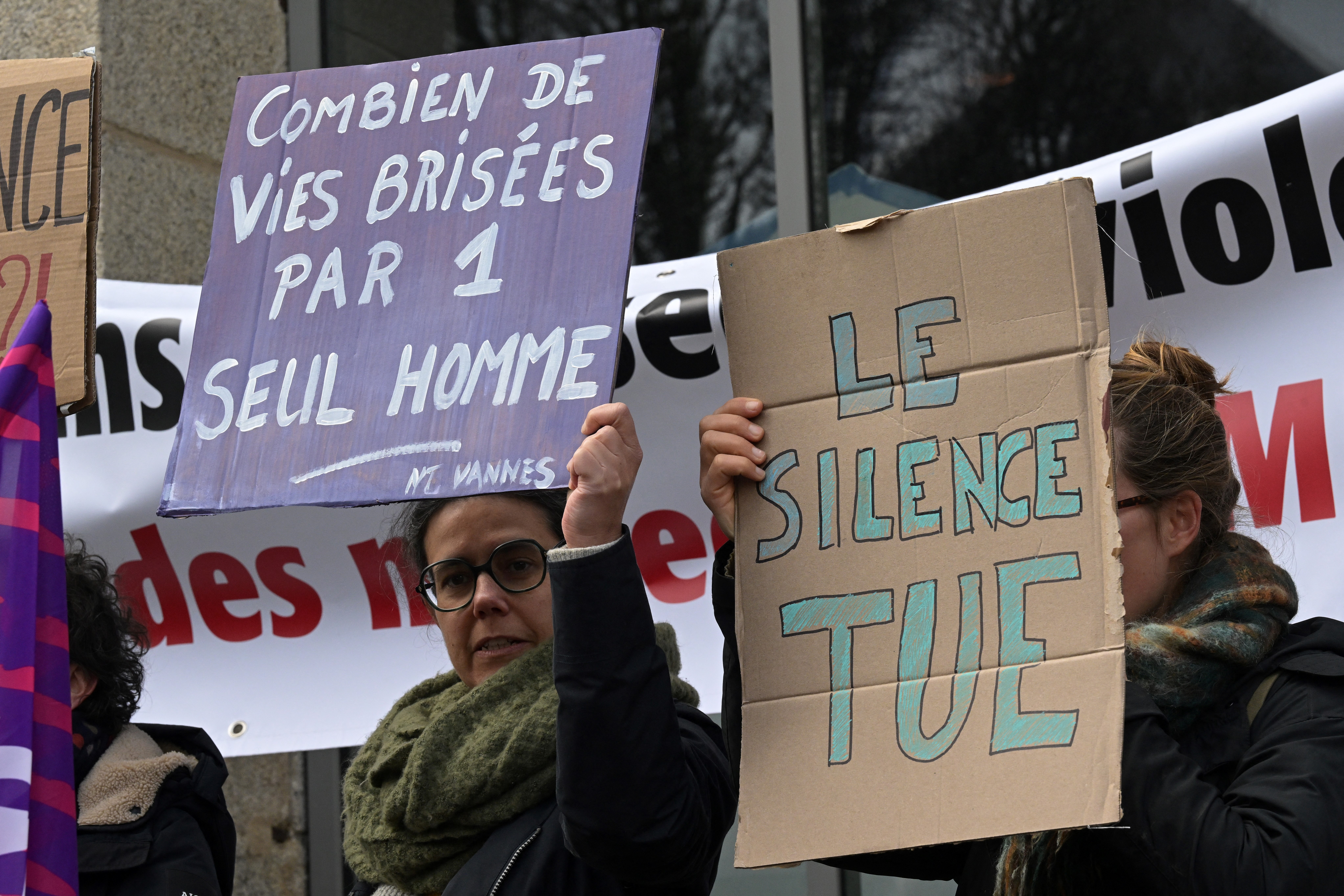 Protesters hold signs reading 'How man lives broken by only one man' and 'Silence kills' outside the Criminal Court in Vannes on the opening day of the trial. /Damien Meyer/AFP
