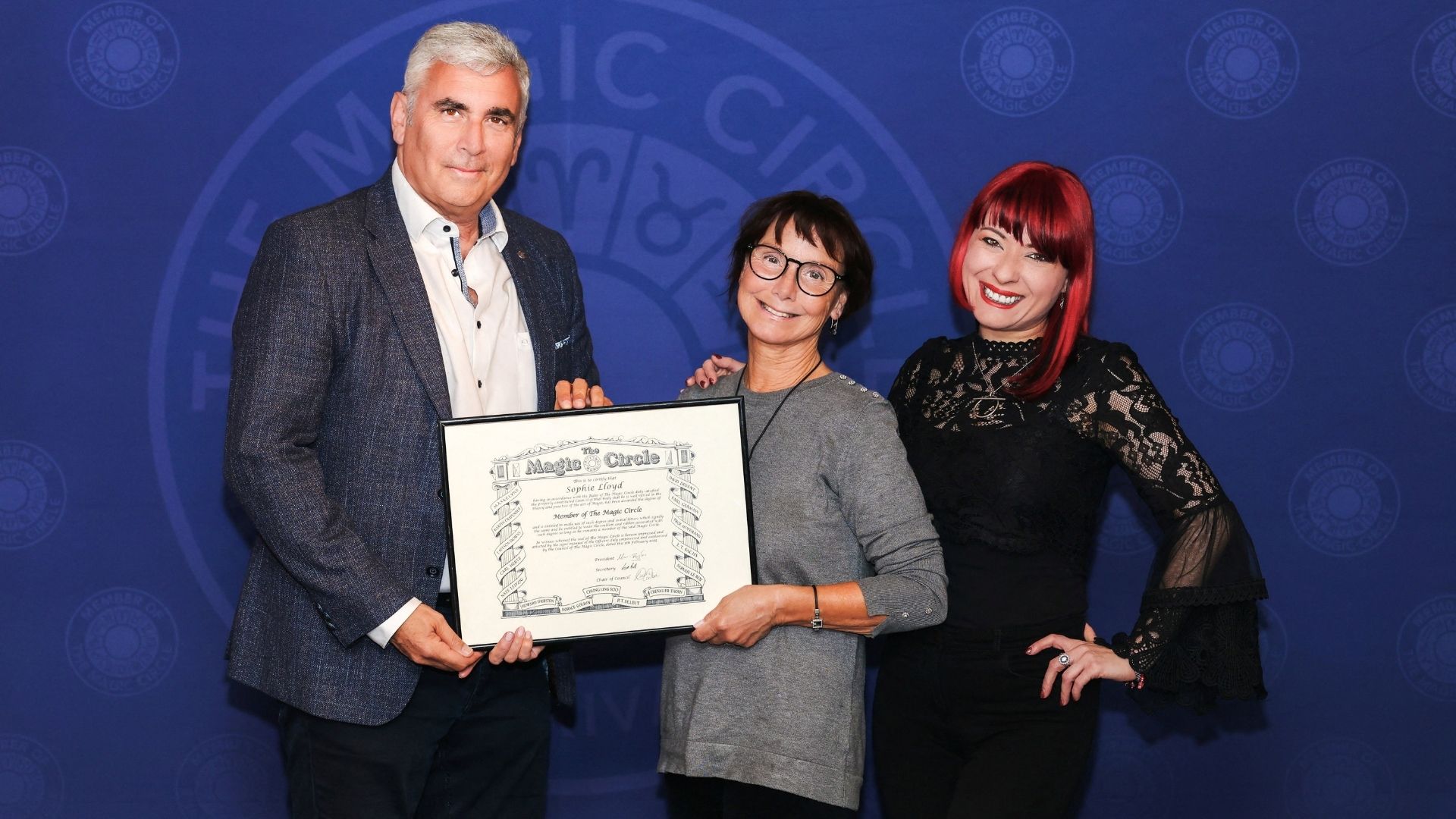 Readmitted to the Magic Circle, Lloyd (C) poses with the group's president Marvin Berglas (L) and chair Laura London. /Brendan Rodrigues/Magic Circle via Reuters