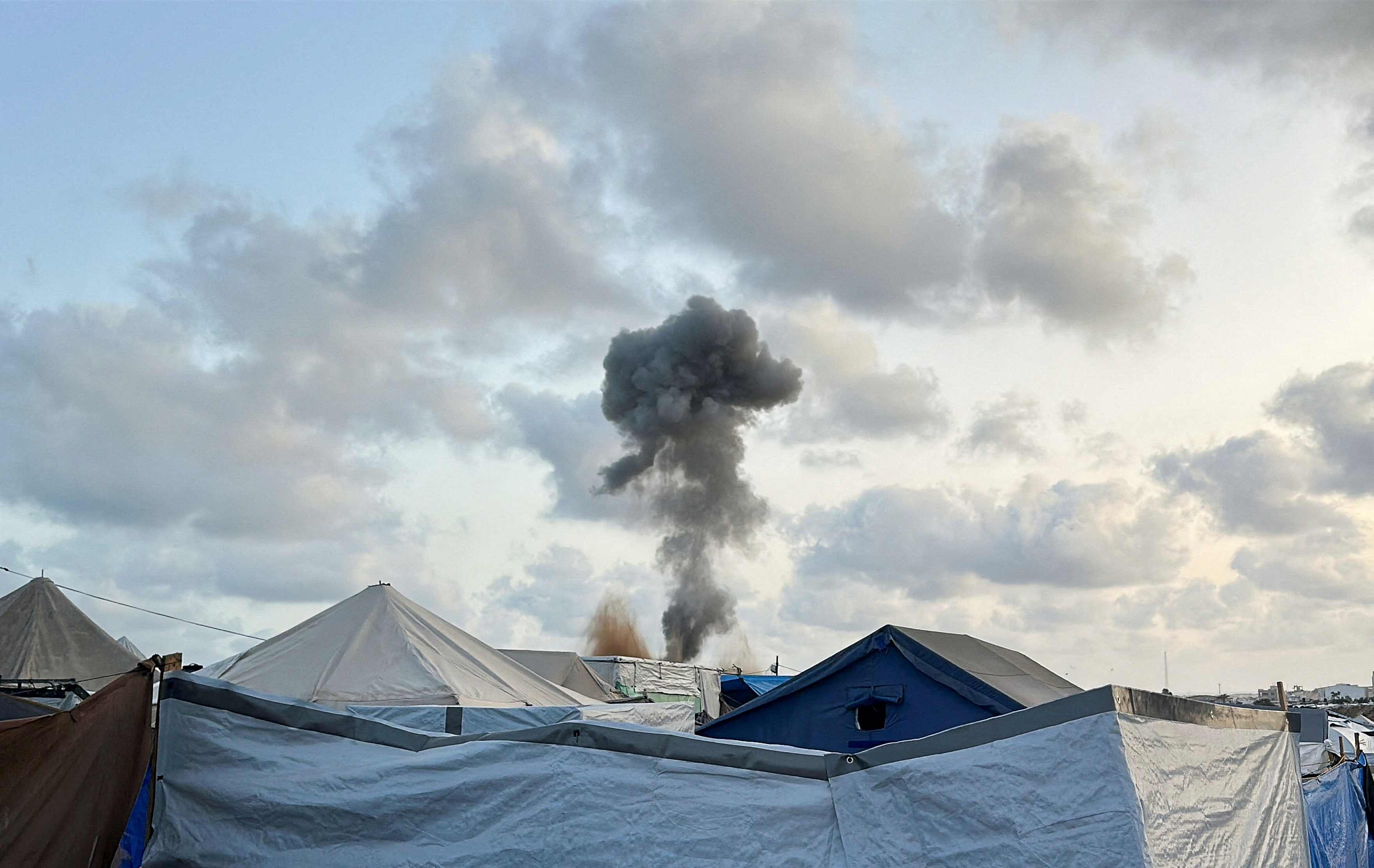 Smoke rises following Israeli strikes, as seen from a tent camp sheltering displaced Palestinians in Khan Younis. /Hatem Khaled/Reuters