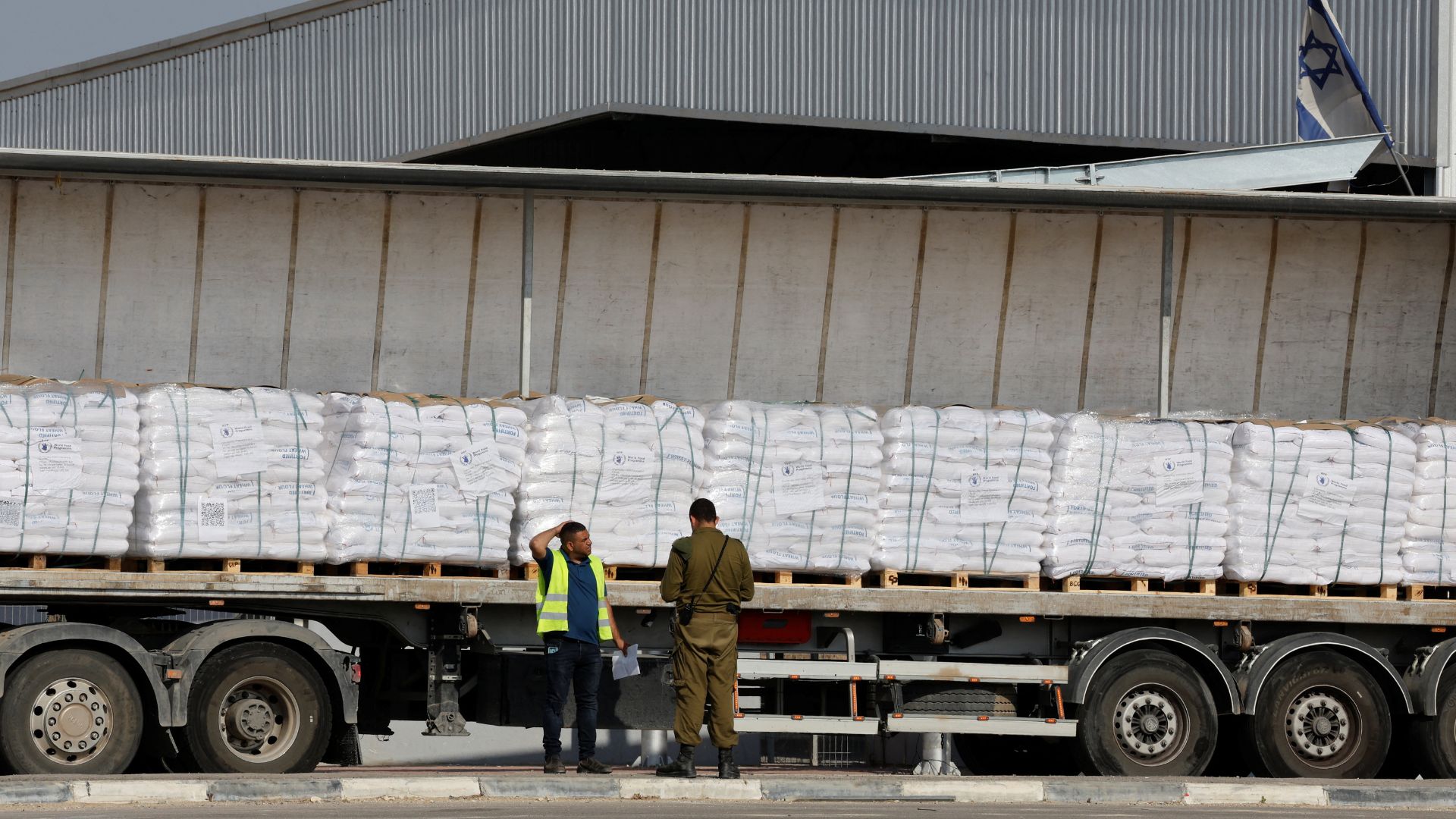 An Israeli security forces member speaks to a worker next to a truck carrying aid at the Kerem Shalom crossing between Israel and Gaza. /Ammar Awad/Reuters