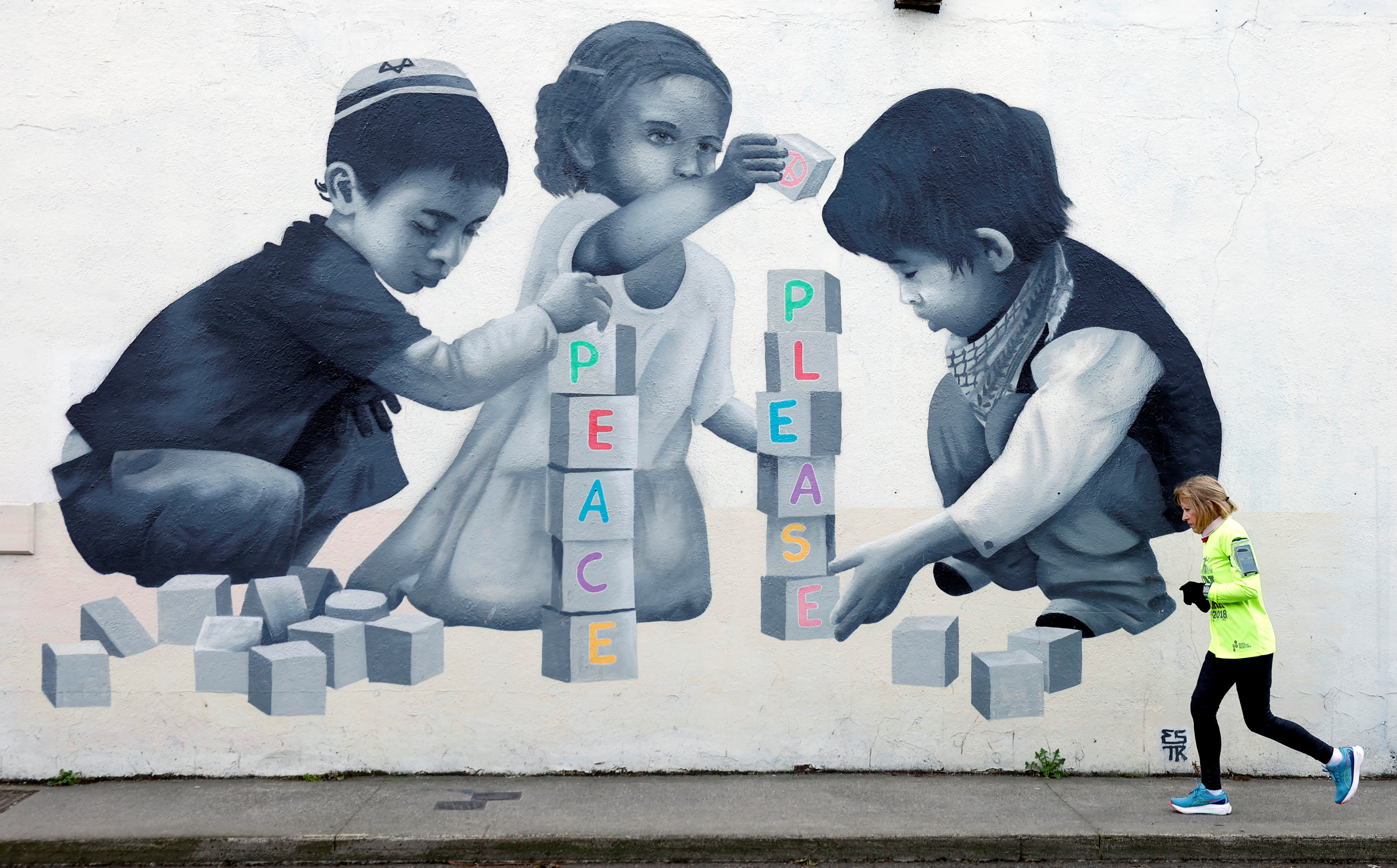 A woman in Dublin jogs past a mural asking for peace, in solidarity with Palestinians in Gaza. /Clodagh Kilcoyne/Reuters