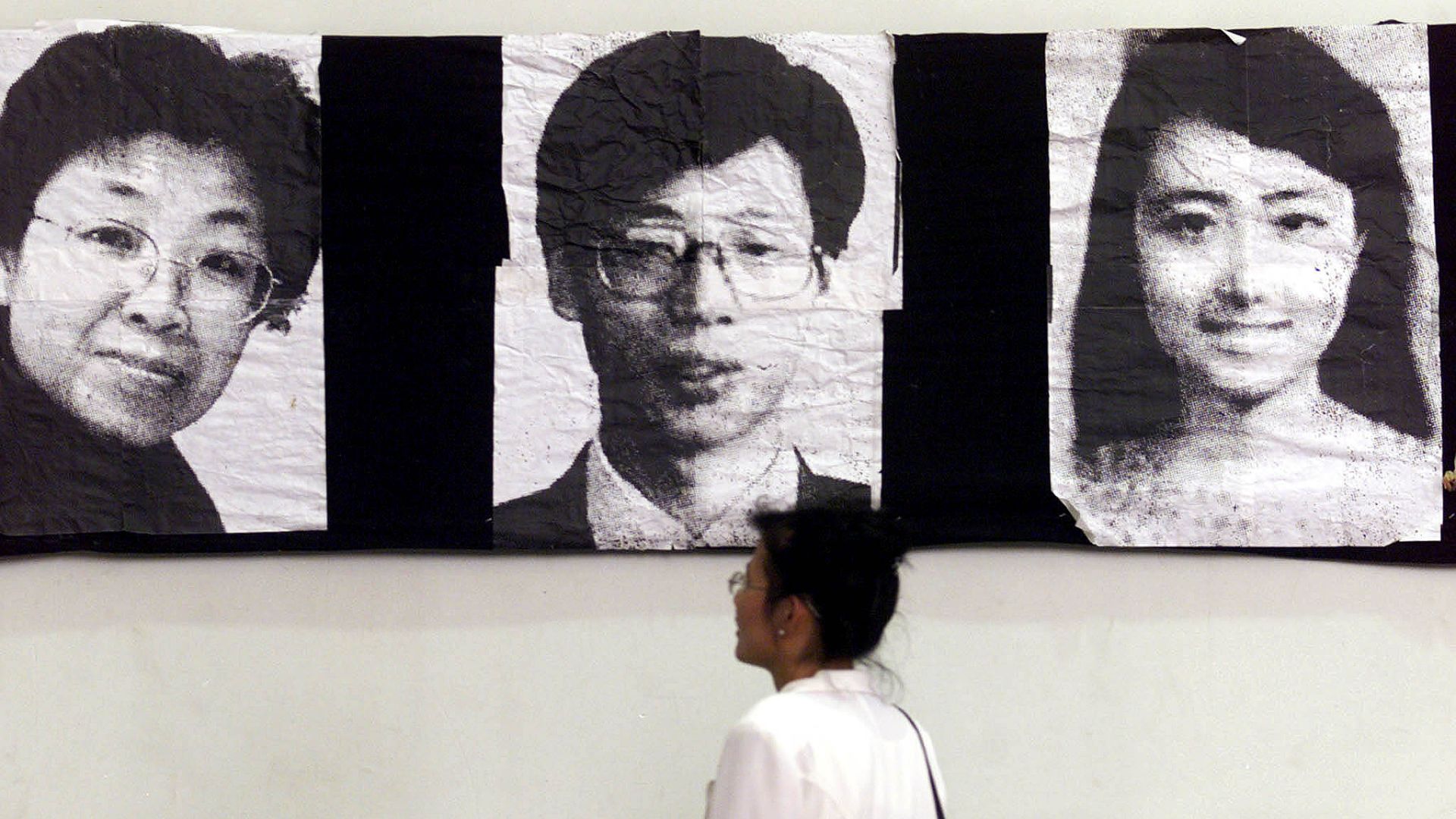 A visitor to an exhibition looks at portraits of three Chinese people killed in NATO's bombing of Beijing's embassy in Belgrade. /Archive/Reuters 
