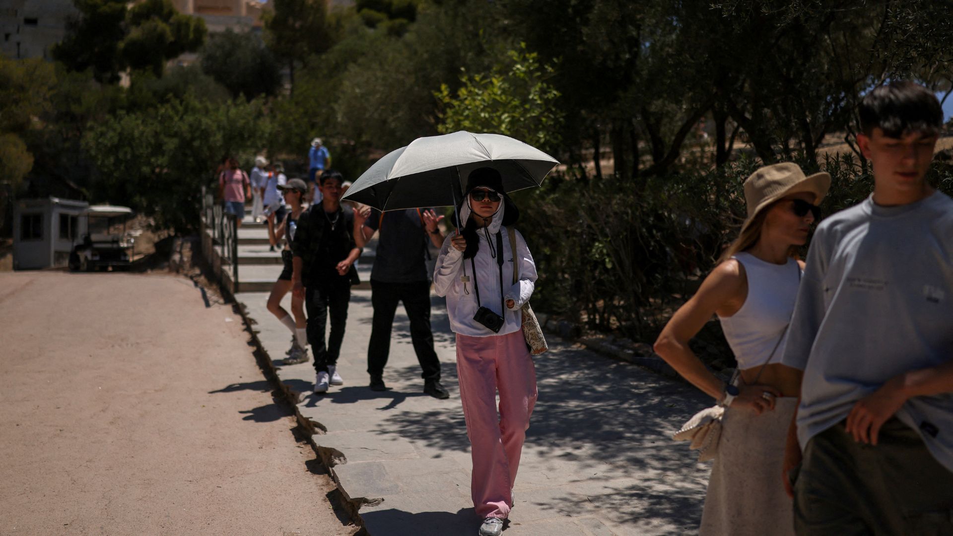 A tourist holds an umbrella to protect from the sun at the Acropolis hill archaeological site, as a heatwave hits Athens. /Stelios Misinas/Reuters