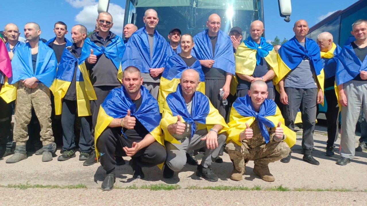 Ukrainian prisoners of war (POWs) are wrapped in Ukrainian flags after a swap at an unknown location in Ukraine. /Handout/Reuters.