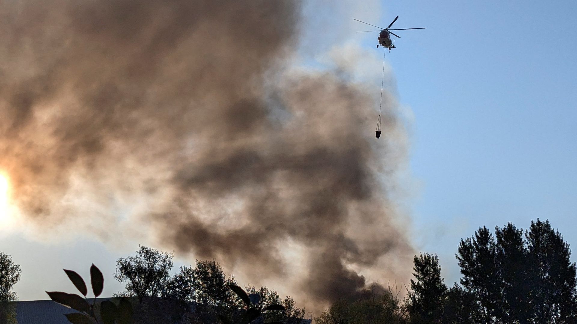 A fire-fighting helicopter collects water to control a fire after a Russian missile and drone strike in Kyiv. /Reuters
