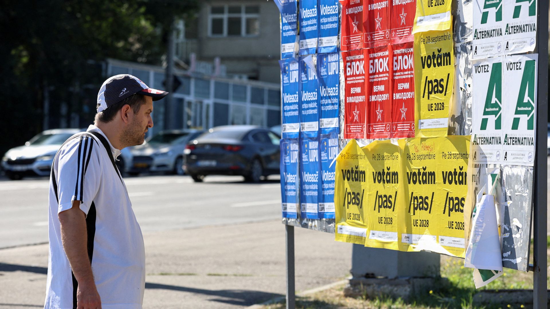 A man stands in front of a board with Moldovan political parties' campaign posters ahead of the upcoming parliamentary elections in Chisinau. /Vladislav Culiomza/Reuters