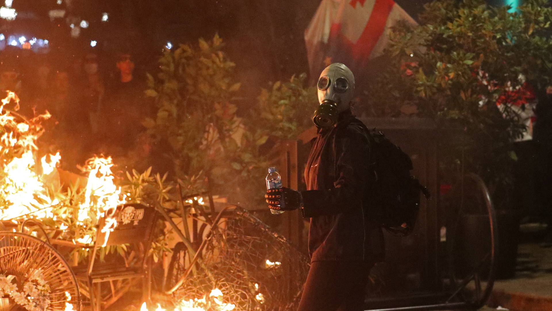 A protester wearing a gas mask stands next to a burning barricade. /Irakli Gedenidze/Reuters