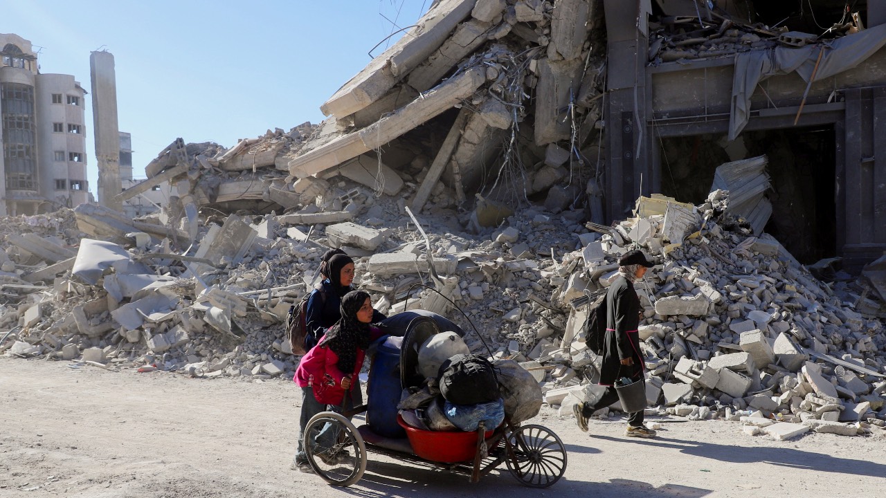 Palestinians push a cart loaded with belongings past the rubble of destroyed buildings in Gaza City. /Ebrahim Hajjaj/Reuters