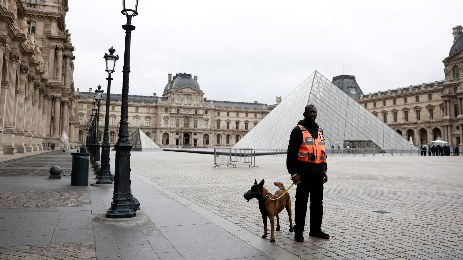 A security employee with a dog stands near the glass Pyramid of the Louvre Museum. /Benoit Tessier/Reuters