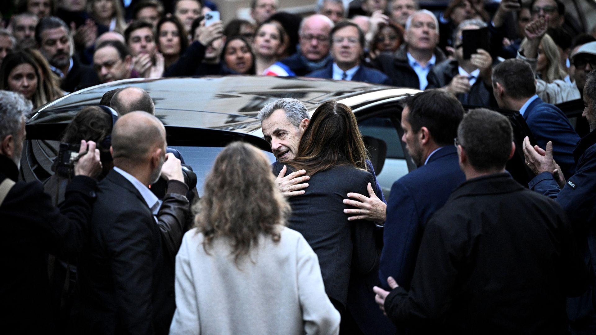 France's former president Nicolas Sarkozy (C) hugs his wife Carla Bruni-Sarkozy as he leaves his residence to present himself to La Sante Prison for incarceration. /Julien De Rosa/AFP

