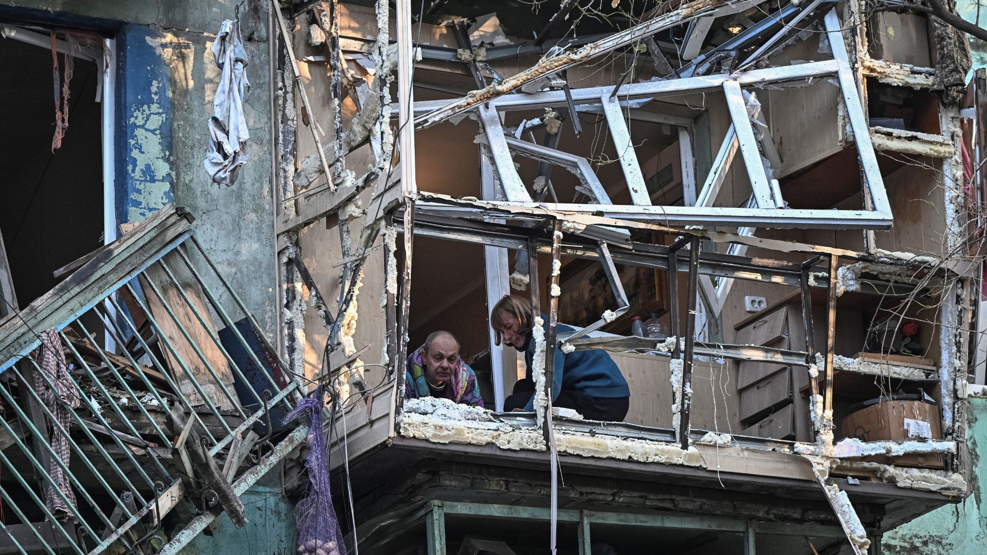 Residents clean the balcony of their Zaporizhzhia flat after a Russian drone strike. /Stringer/Reuters