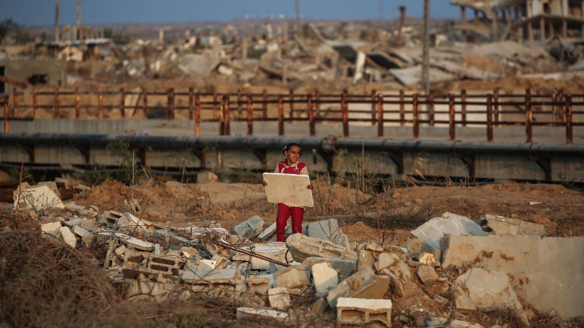 A young Palestinian girl picks up a piece of rubble in Nuseirat, Gaza Strip. /Eyad Baba/AFP