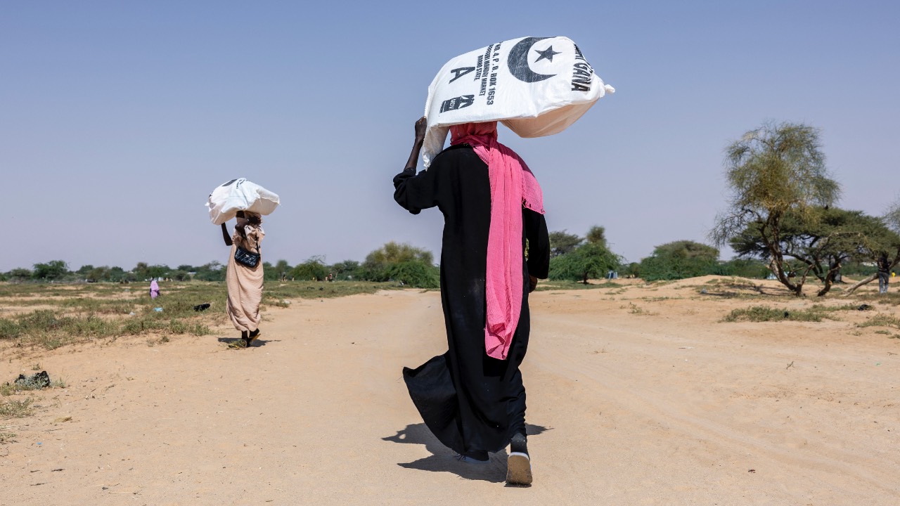 Sudanese refugees carrying kits distributed by the Red Cross leave the registration area at Oure Cassoni camp in Chad. /Joris Bolomey/AFP