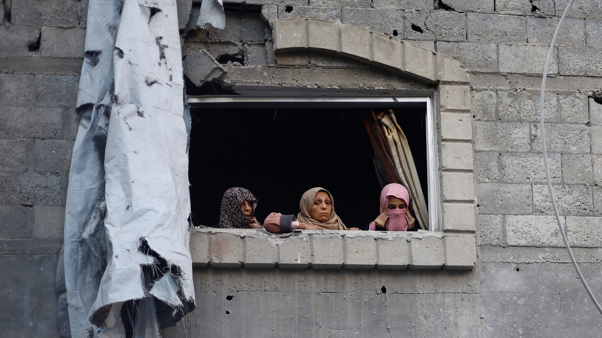 Palestinian women look out of a window near the site of Saturday's Israeli strike in the Central Gaza Strip. Mahmoud Issa/Reuters
