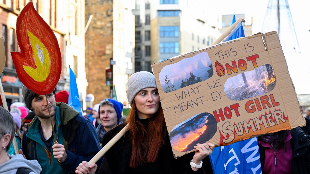 A person holds a placard during a climate-justice activists' march as part of nationwide protests calling for stronger global climate action, during the  UN Climate Change Conference (COP30), in Glasgow, Scotland. /Lesley Martin/Reuters