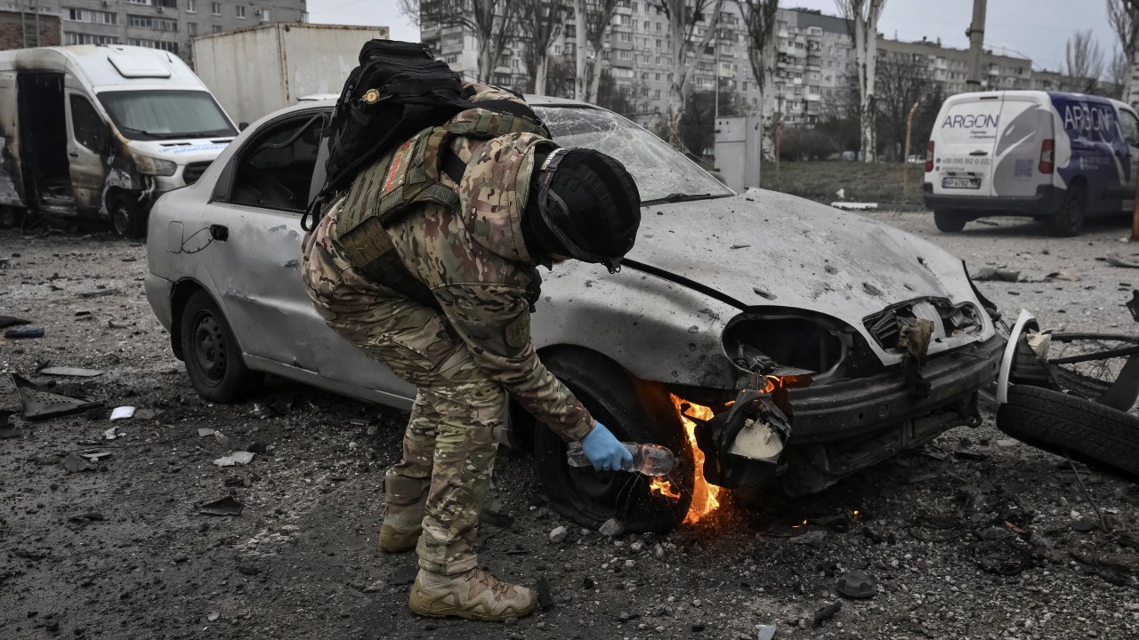 A police officer puts out a burning car at the site of the Russian drone strike in Zaporizhzhia, Ukraine. /Reuters