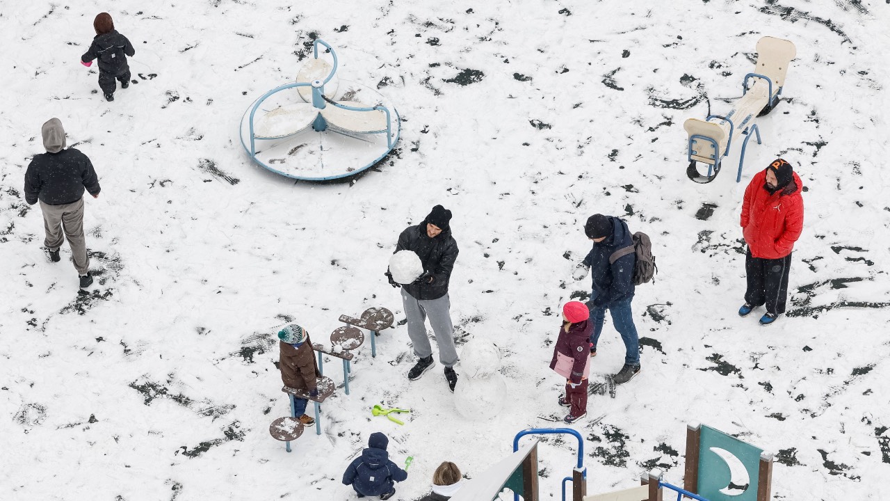 People with children make a snowman on a playground covered in snow during the first snowfall in Kyiv, Ukraine. /Gleb Garanich/Reuters