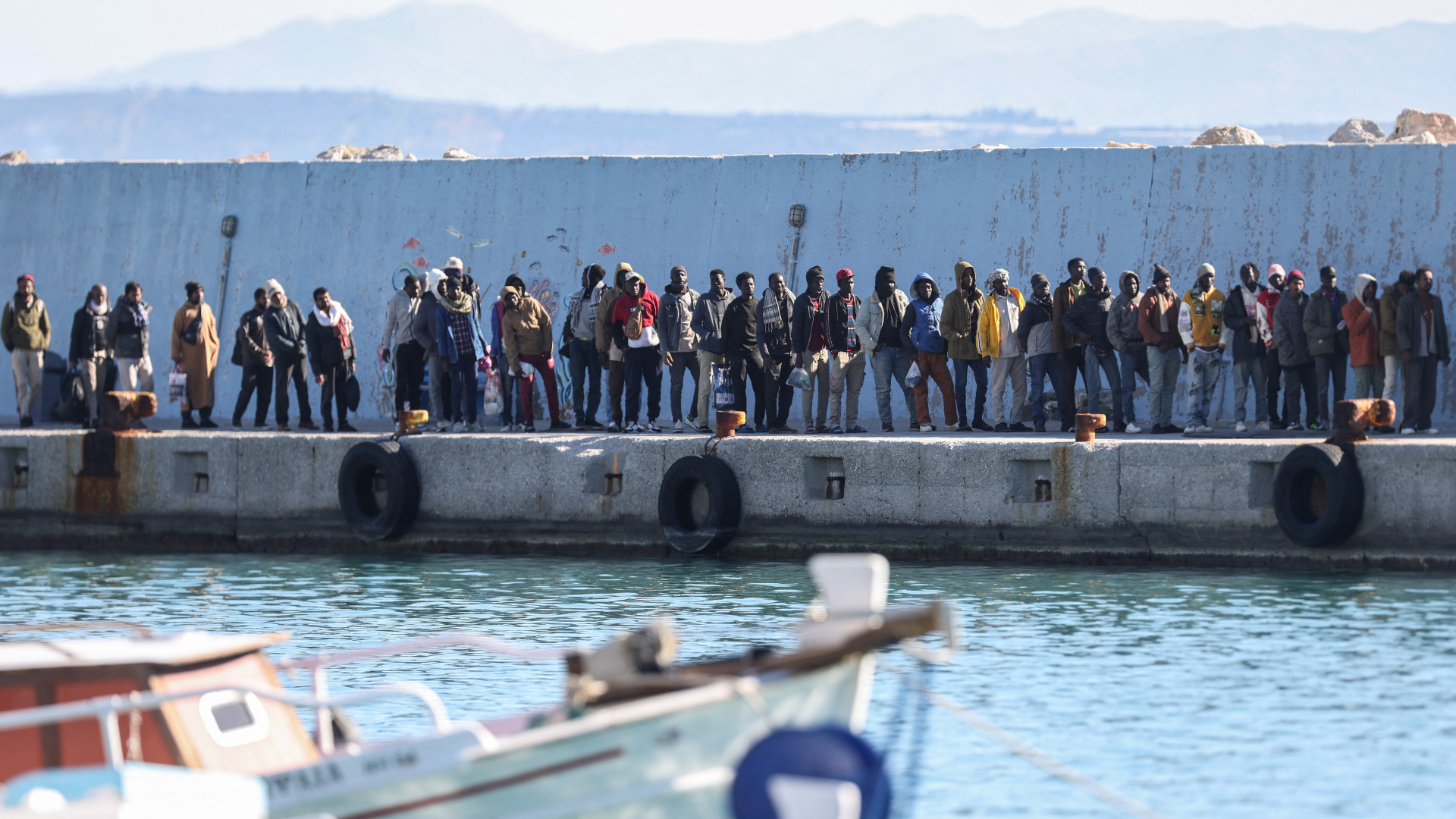 A group of migrants, found during a search operation off Gavdos island, waits to be transferred to island's temporary facility, in the port of Agia Galini, Crete island, Greece. /Stefanos Rapanis/Reuters
